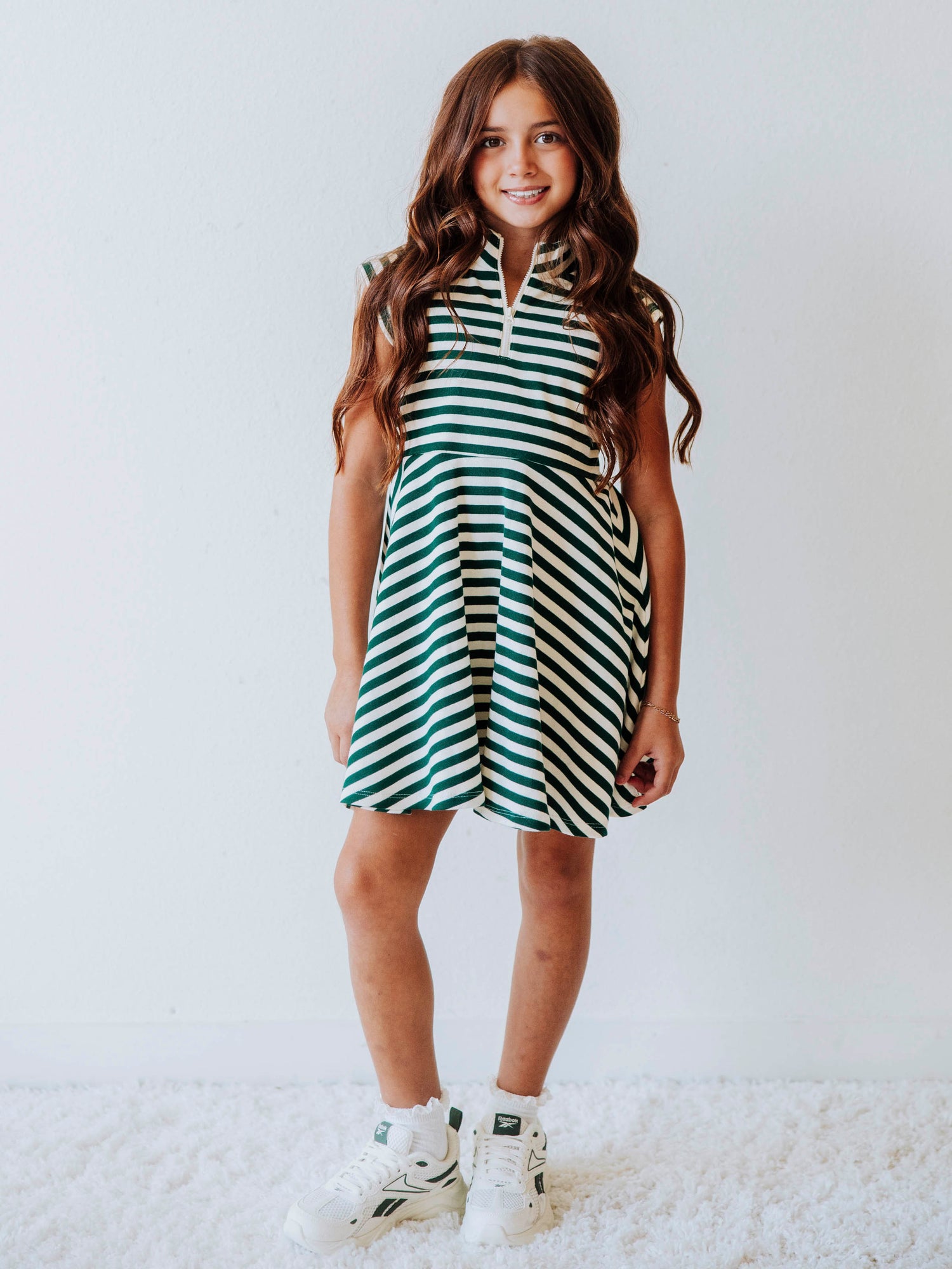 Model wearing a green and ivory striped dress. Dress has a zipper closure at chest. 