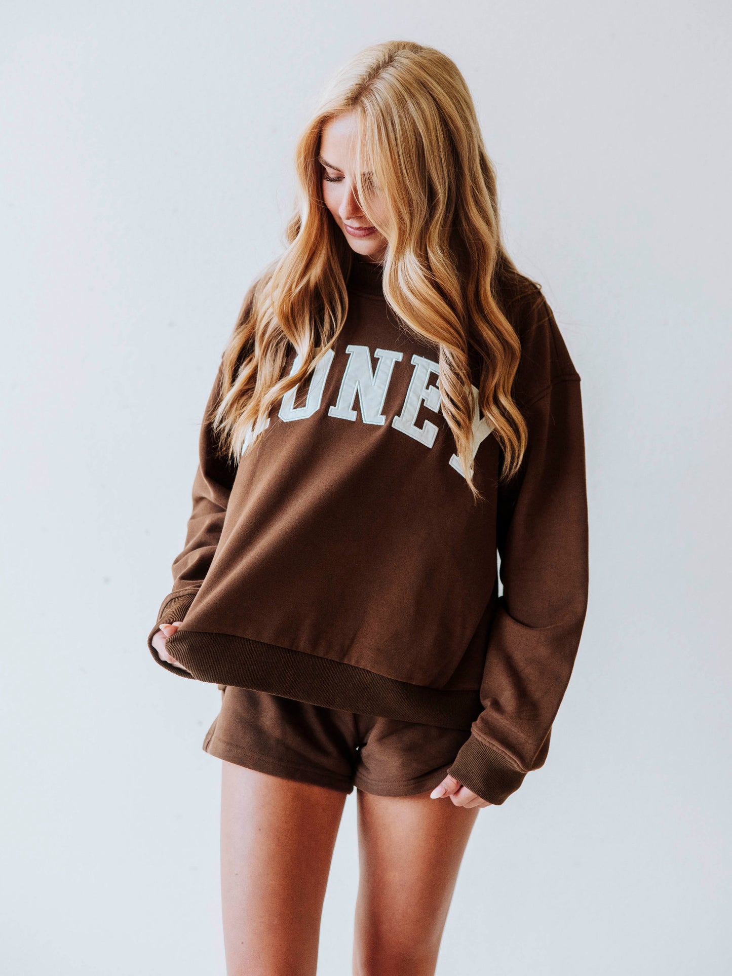 Girl wearing a chocolate brown mock neck sweatshirt  set that says HONEY on the front. Bottoms are the same chocolate brown as top.