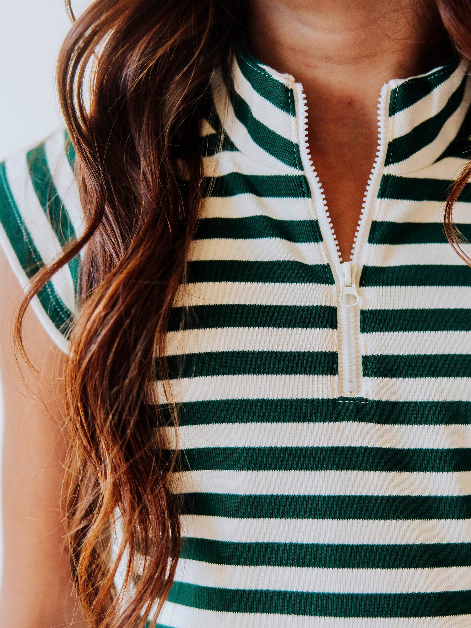 Close up picture of green and ivory striped dress with zipper closure at chest. 