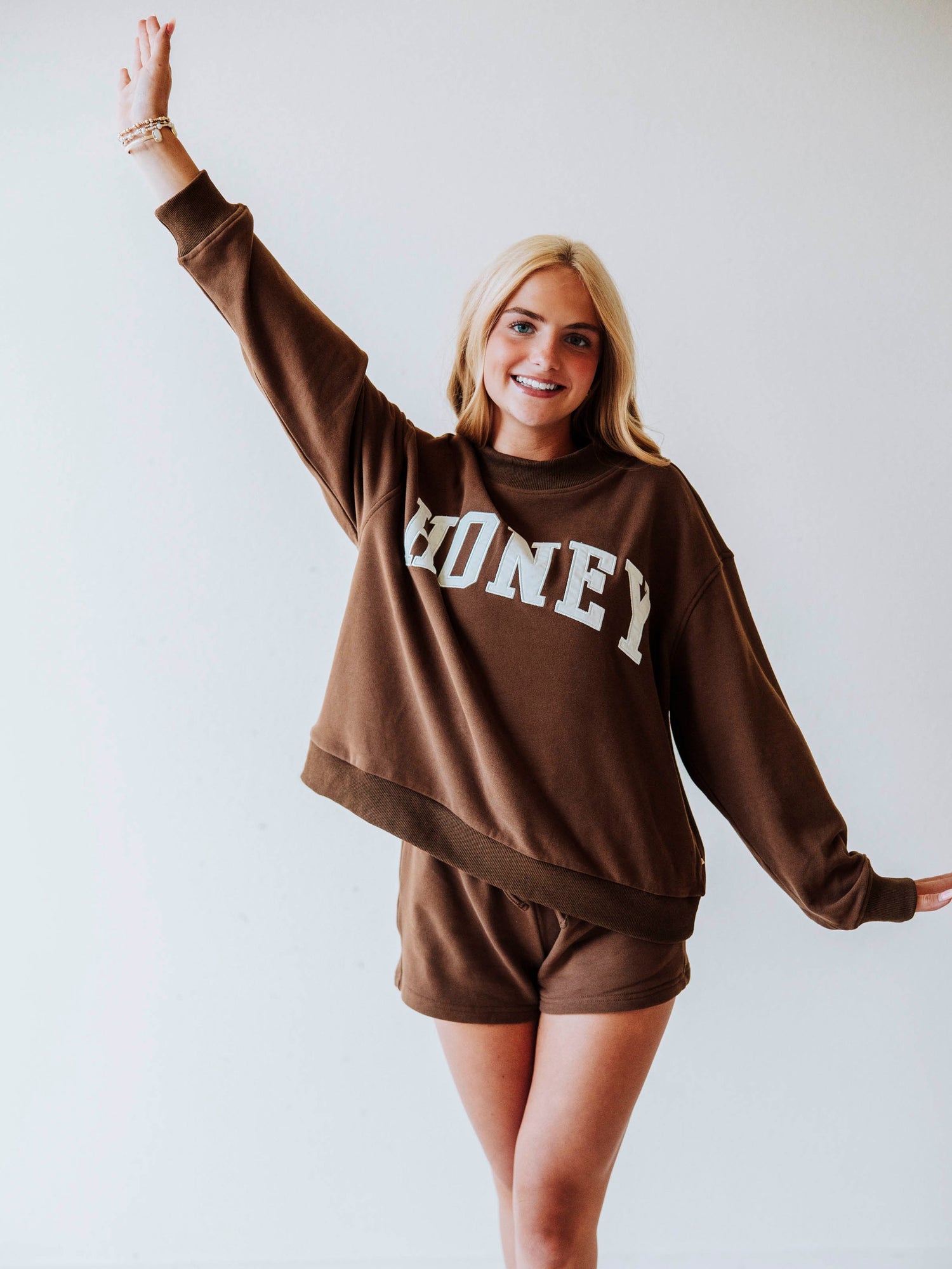 Girl wearing a chocolate brown mock neck sweatshirt  set that says HONEY on the front. Bottoms are the same chocolate brown as top.