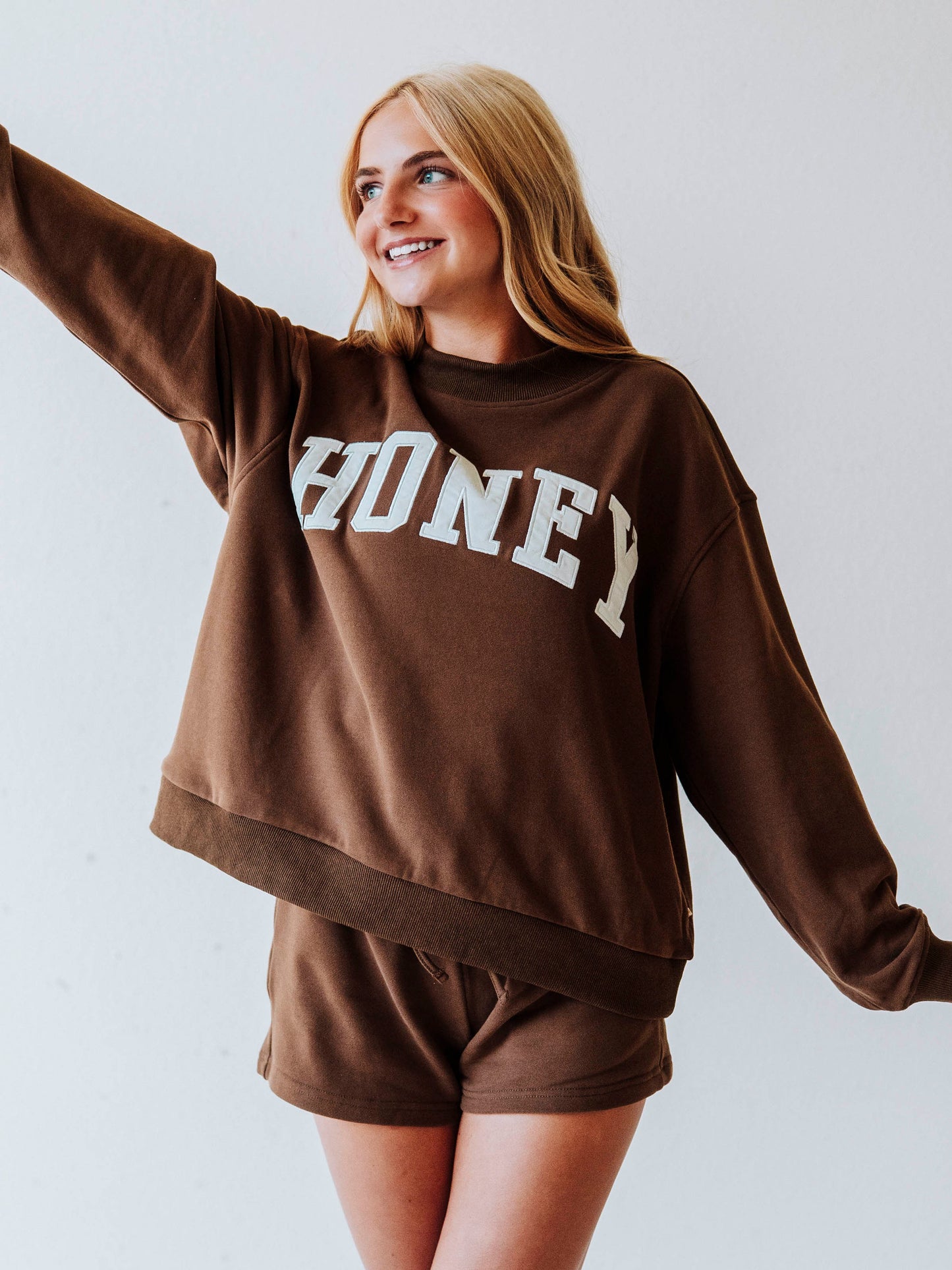 Girl wearing a chocolate brown mock neck sweatshirt  set that says HONEY on the front. Bottoms are the same chocolate brown as top.