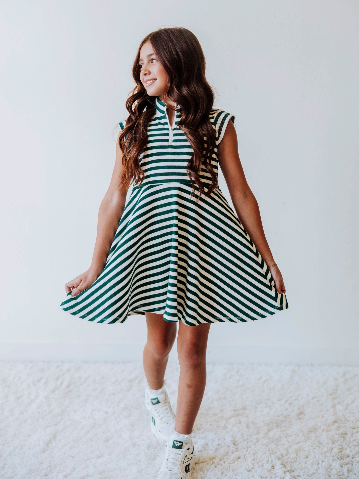 Model wearing a green and ivory striped dress. Dress has a zipper closure at chest. 