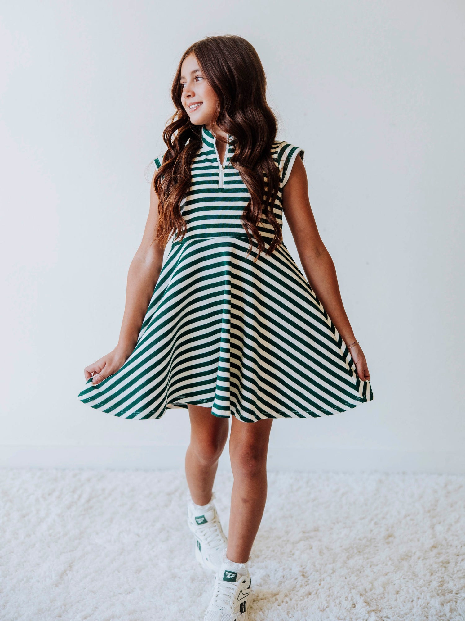 Model wearing a green and ivory striped dress. Dress has a zipper closure at chest. 