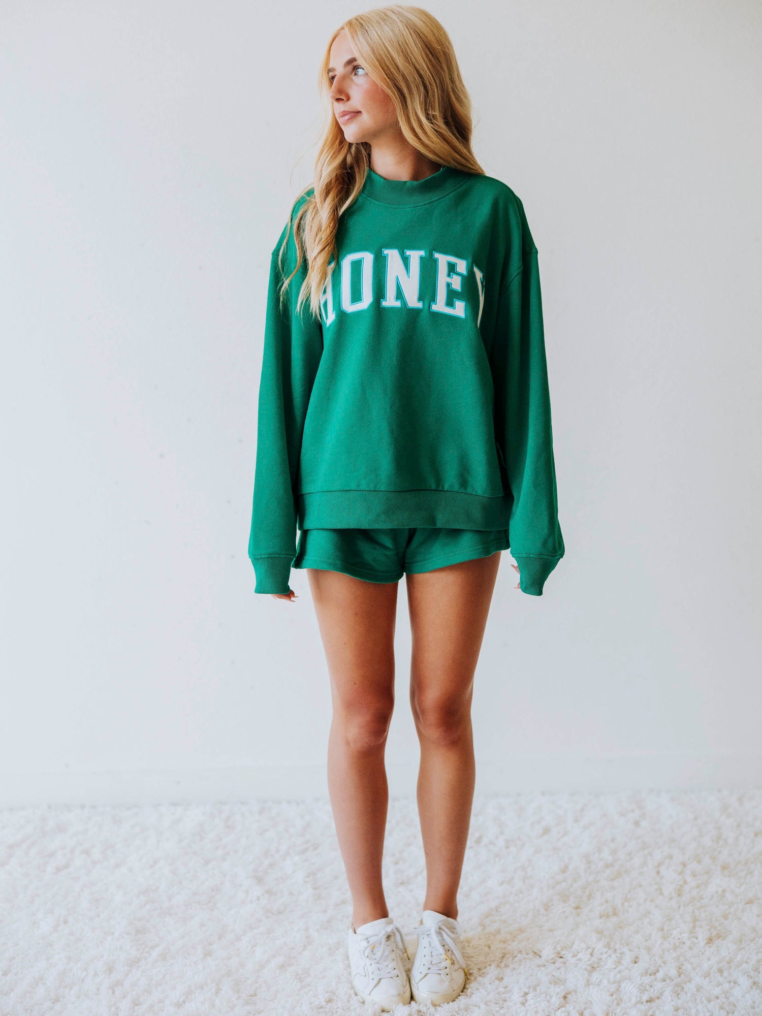 Girl wearing a teal two piece set. Top says HONEY on the front. Shorts are same teal color as top. 
