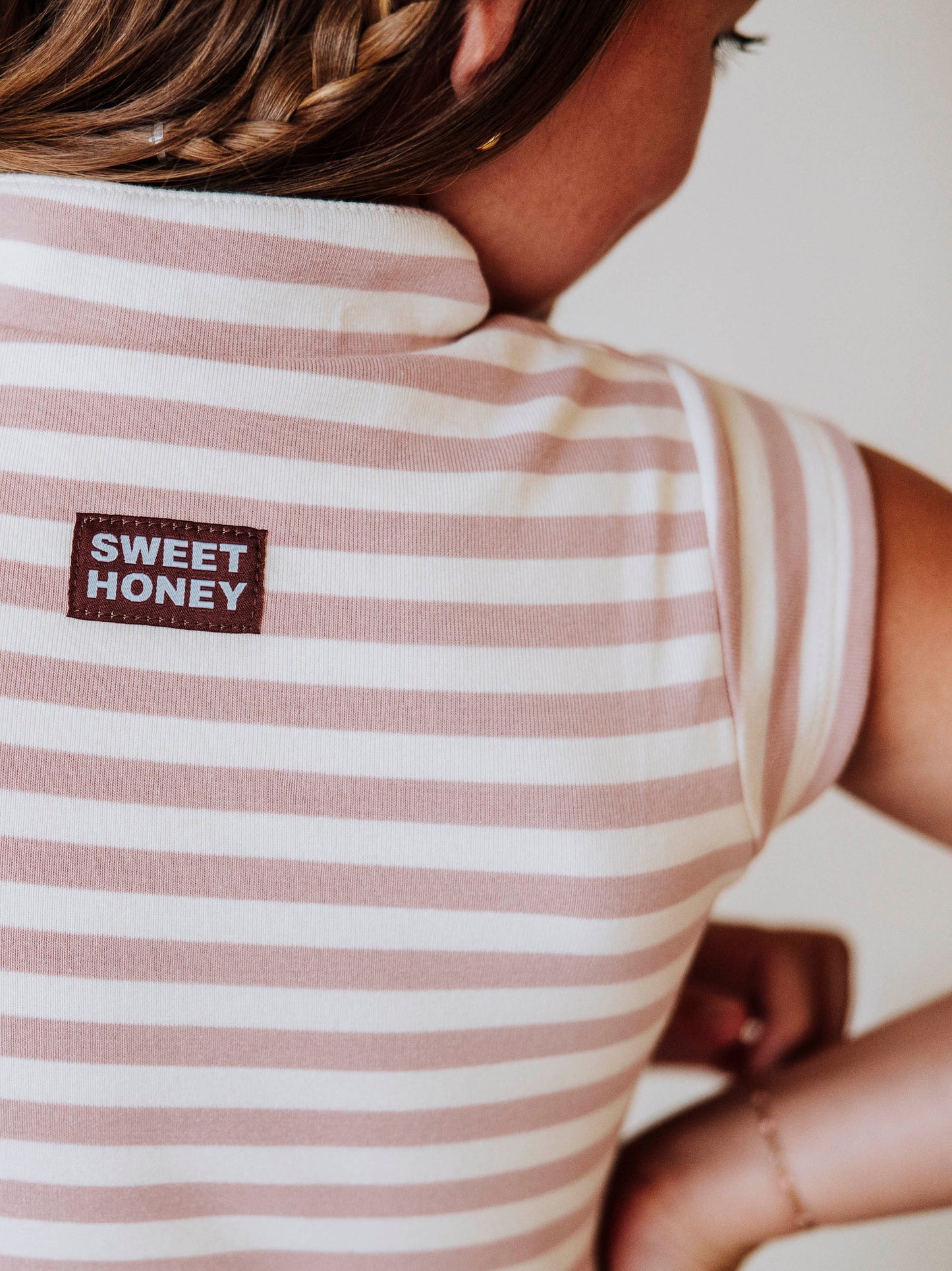 Close up of SweetHoney tag stitched at back of pink and ivory dress. 