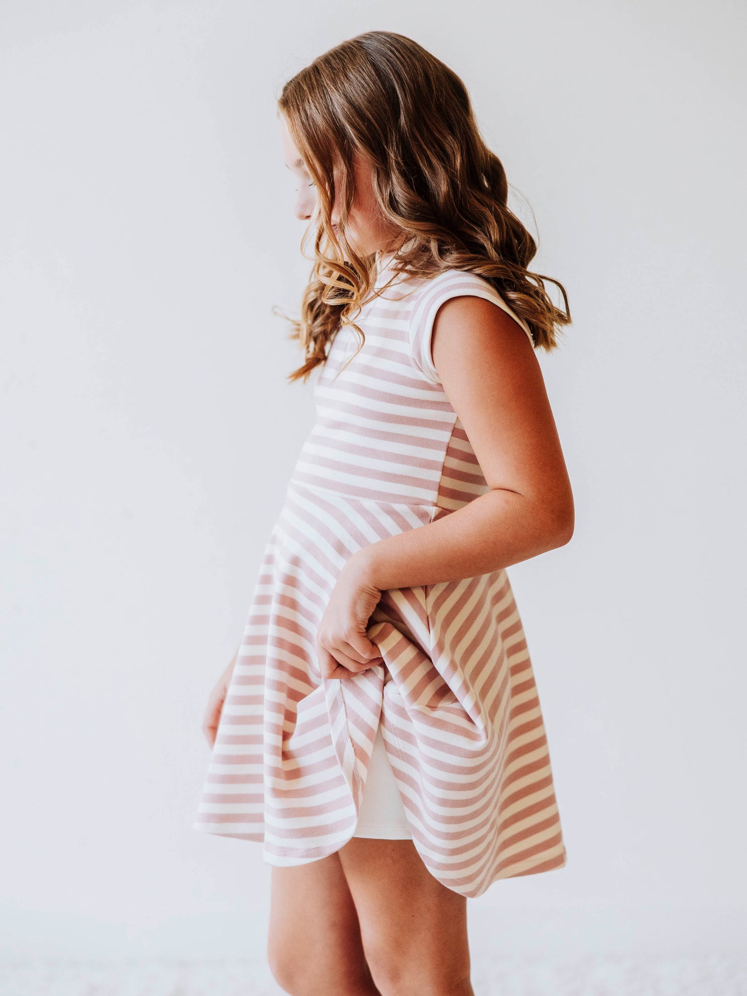 Model is slightly pulling up the side of her pink and ivory dress to show a pair of ivory gym shorts underneath. 