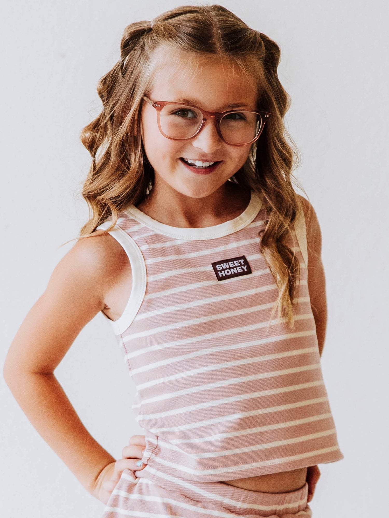 Model is wearing a pink and ivory striped two piece skort set. There is a sweethoney stitched tag on the middle of chest of shirt. 