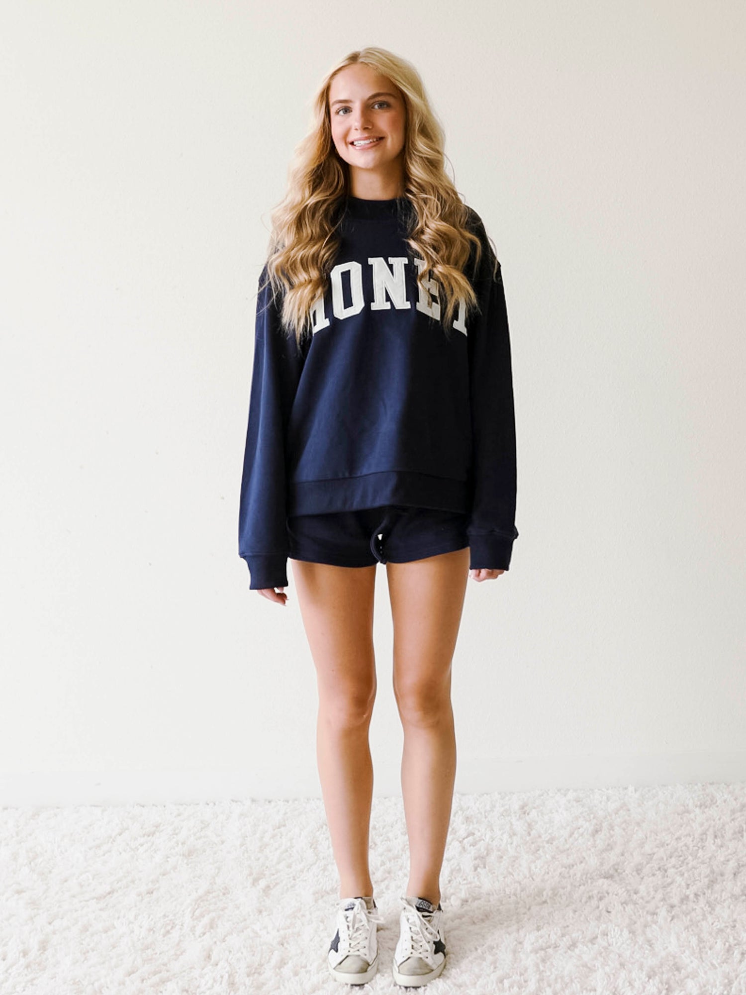 Girl wearing a two piece, navy colored set. The top is a mock neck style that says HONEY on the front and the bottoms are also navy in color.