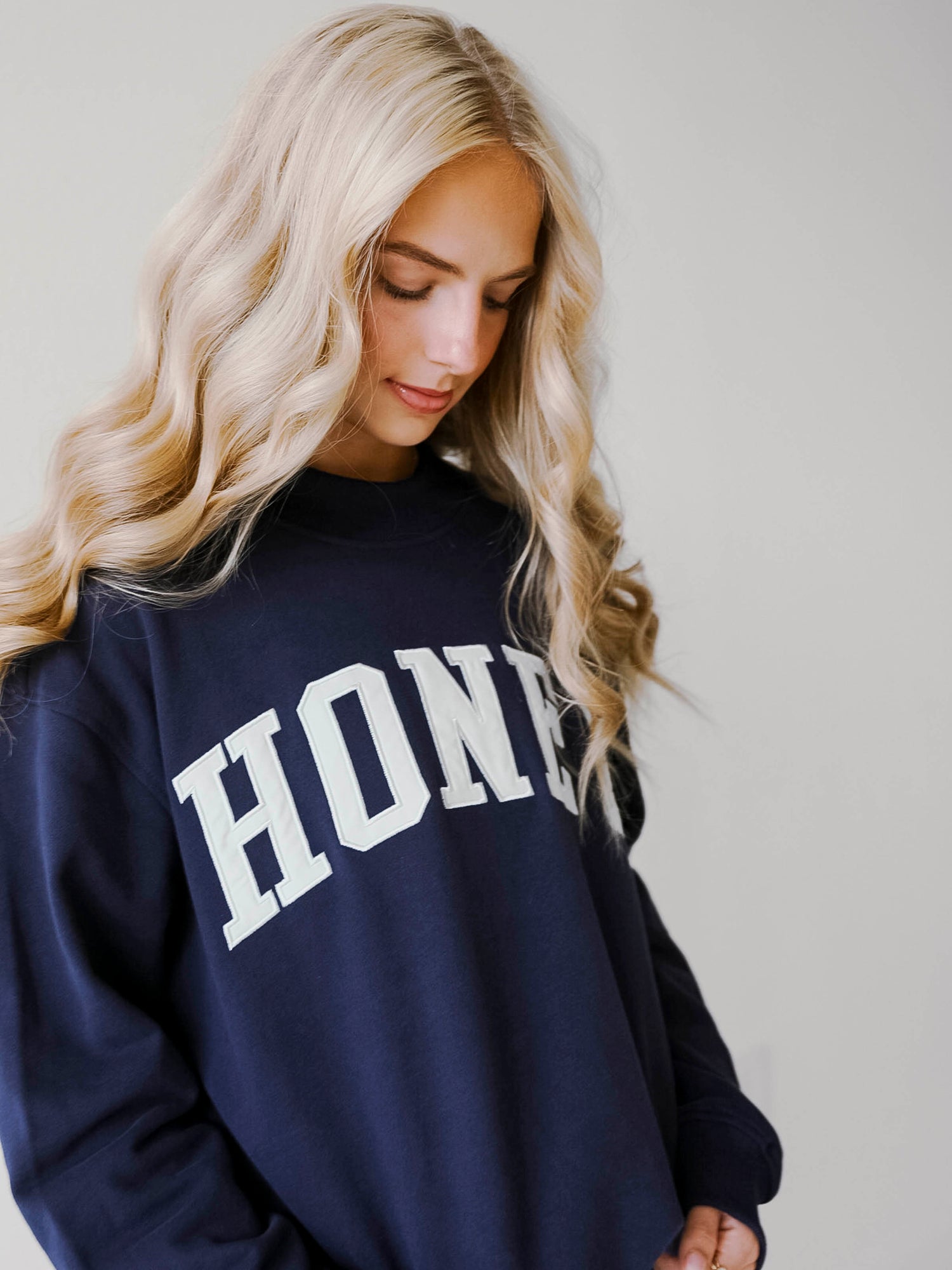 Girl wearing a two piece, navy colored set. The top is a mock neck style that says HONEY on the front and the bottoms are also navy in color.