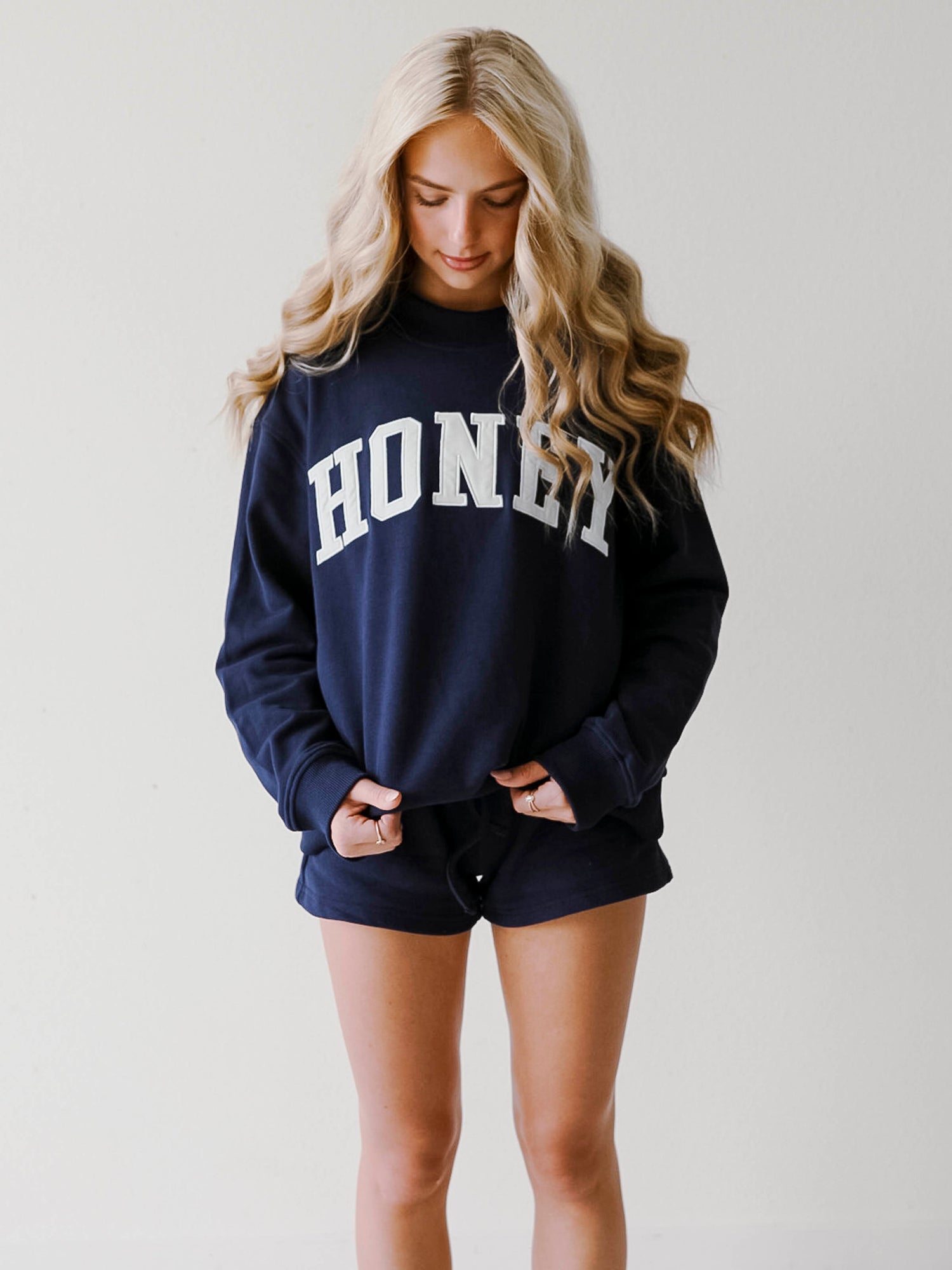 Girl wearing a two piece, navy colored set. The top is a mock neck style that says HONEY on the front and the bottoms are also navy in color.