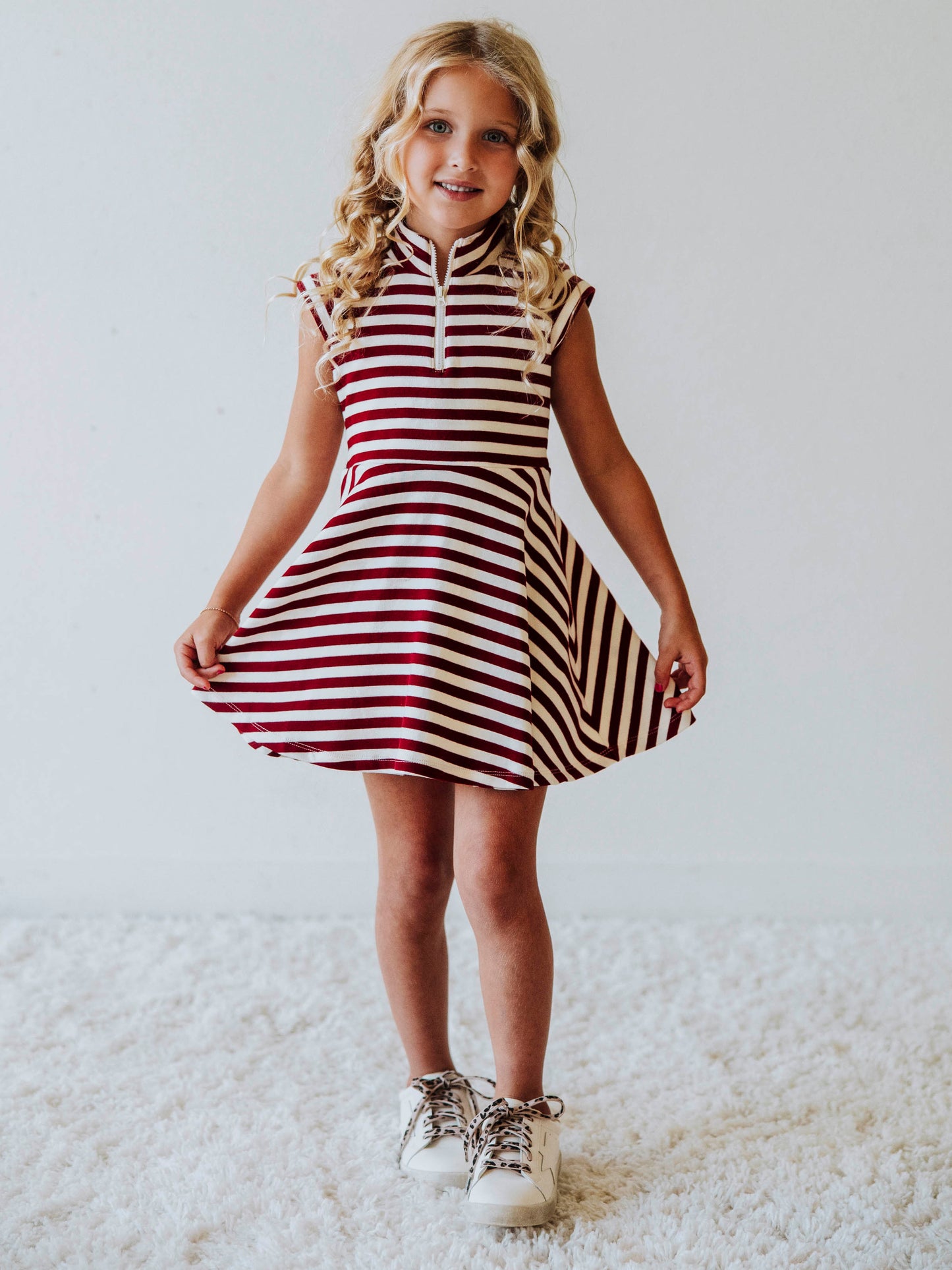 Model wearing a brown and ivory striped dress with white shoes. 