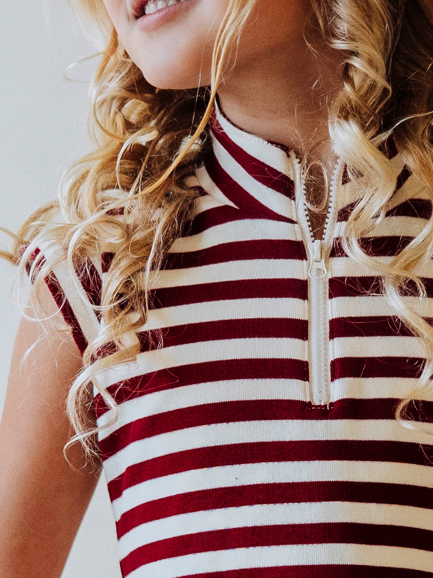 Up close picture of the zipper closure on a crimson and ivory striped dress. 
