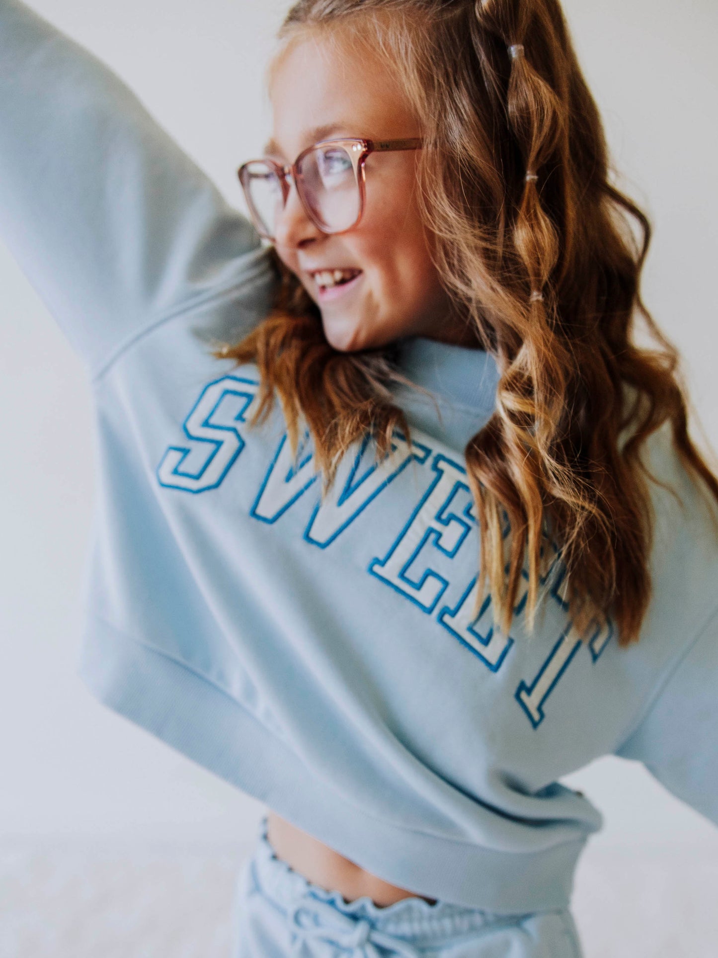 Close up of Model wearing a light blue two piece jogging set. Top says SWEET and the bottoms are the same color blue as top. 