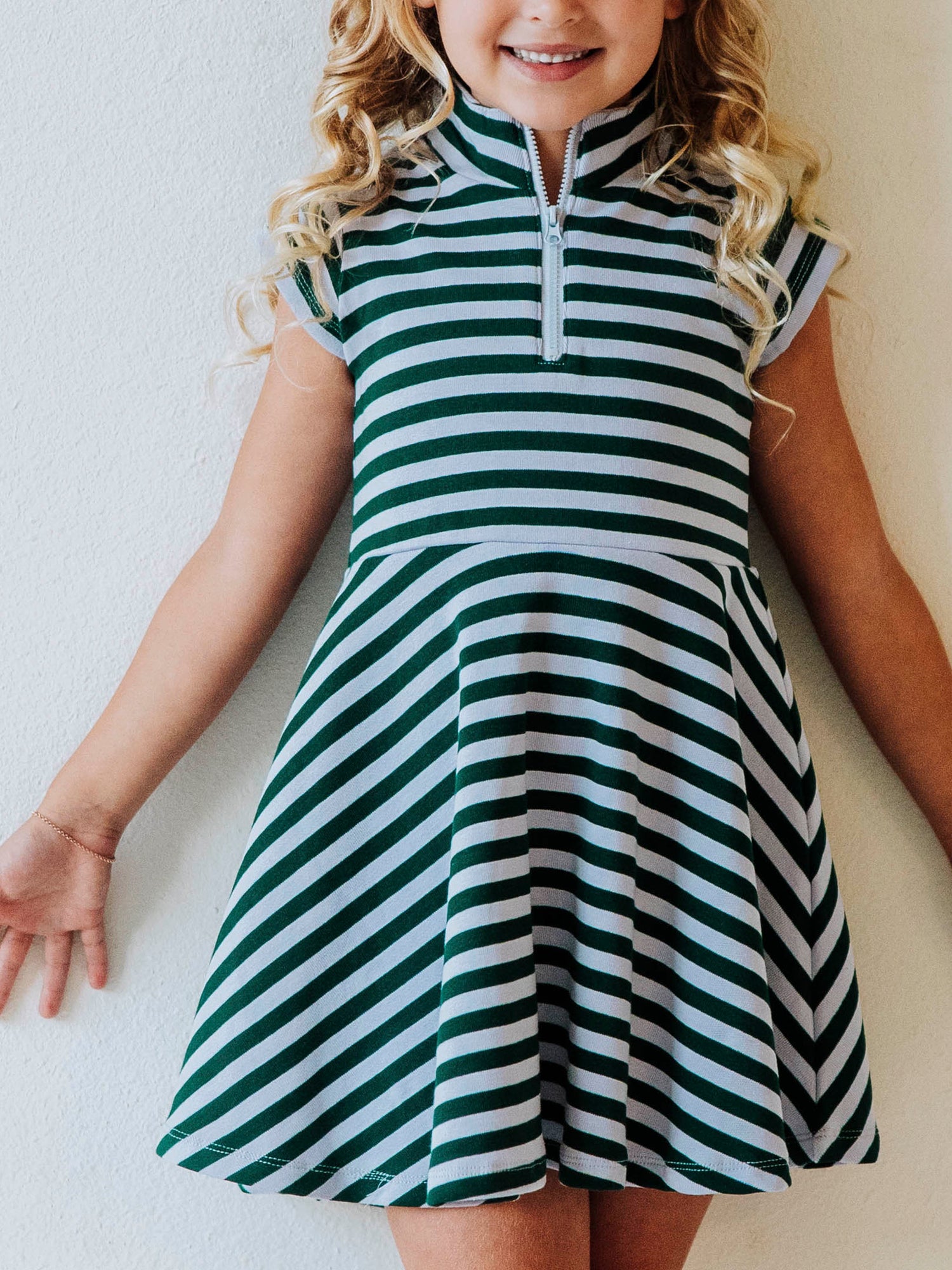 Model wearing a green and gray striped dress that has cap sleeves and a zipper closure at chest. 