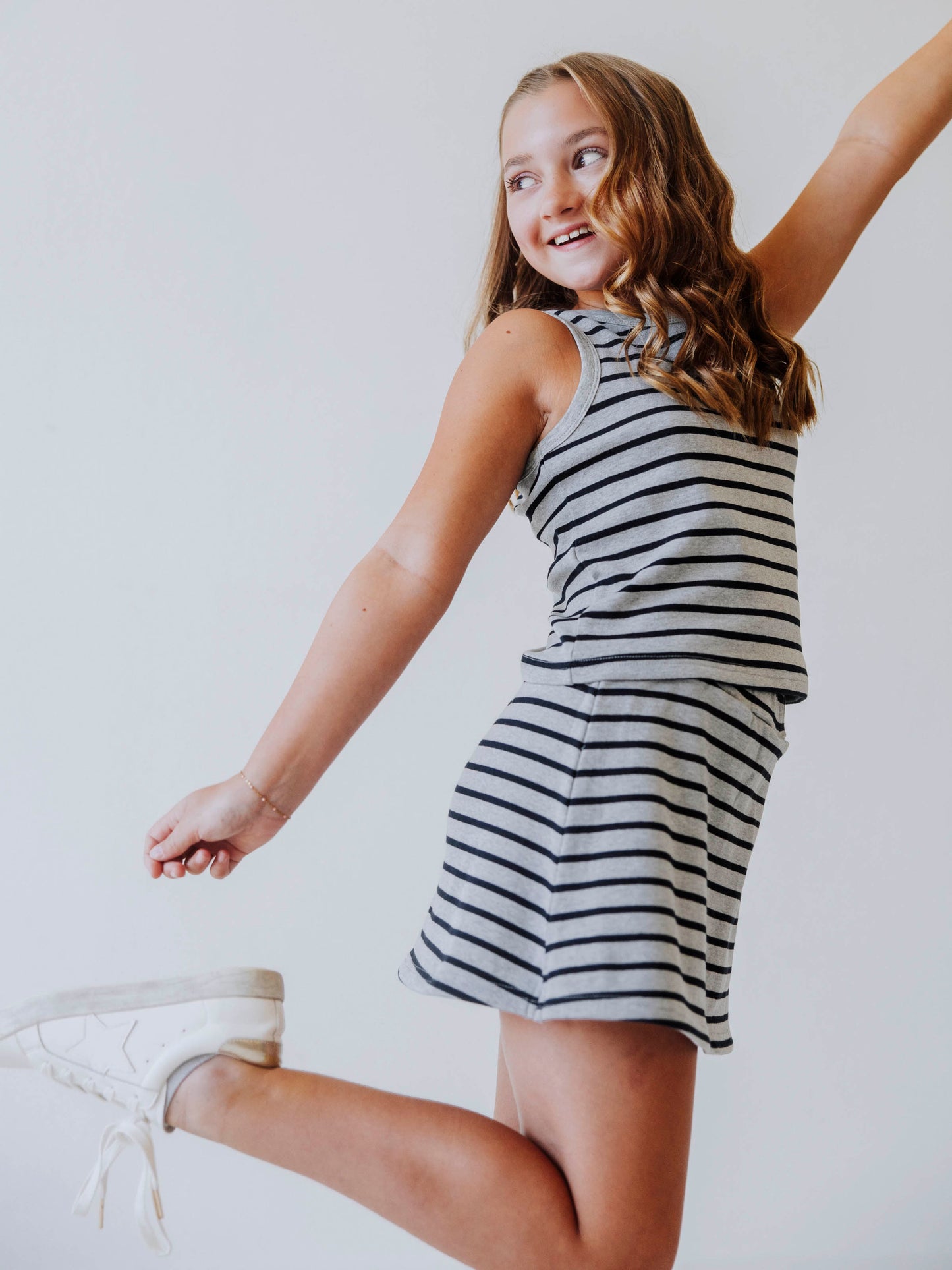 Posing model wearing a navy and gray, two piece skort set. Model is also wearing white shoes. 