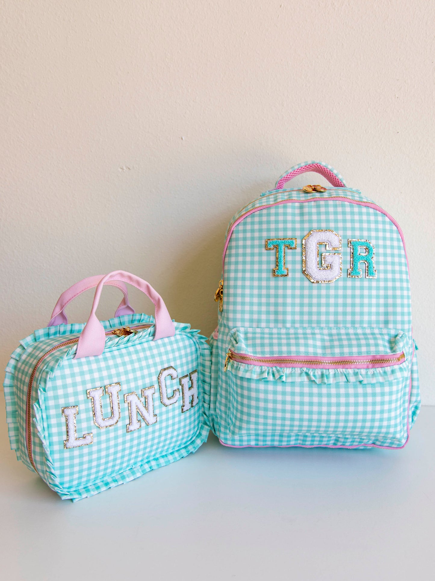 Mint green backpack and lunch kit both with letter patches