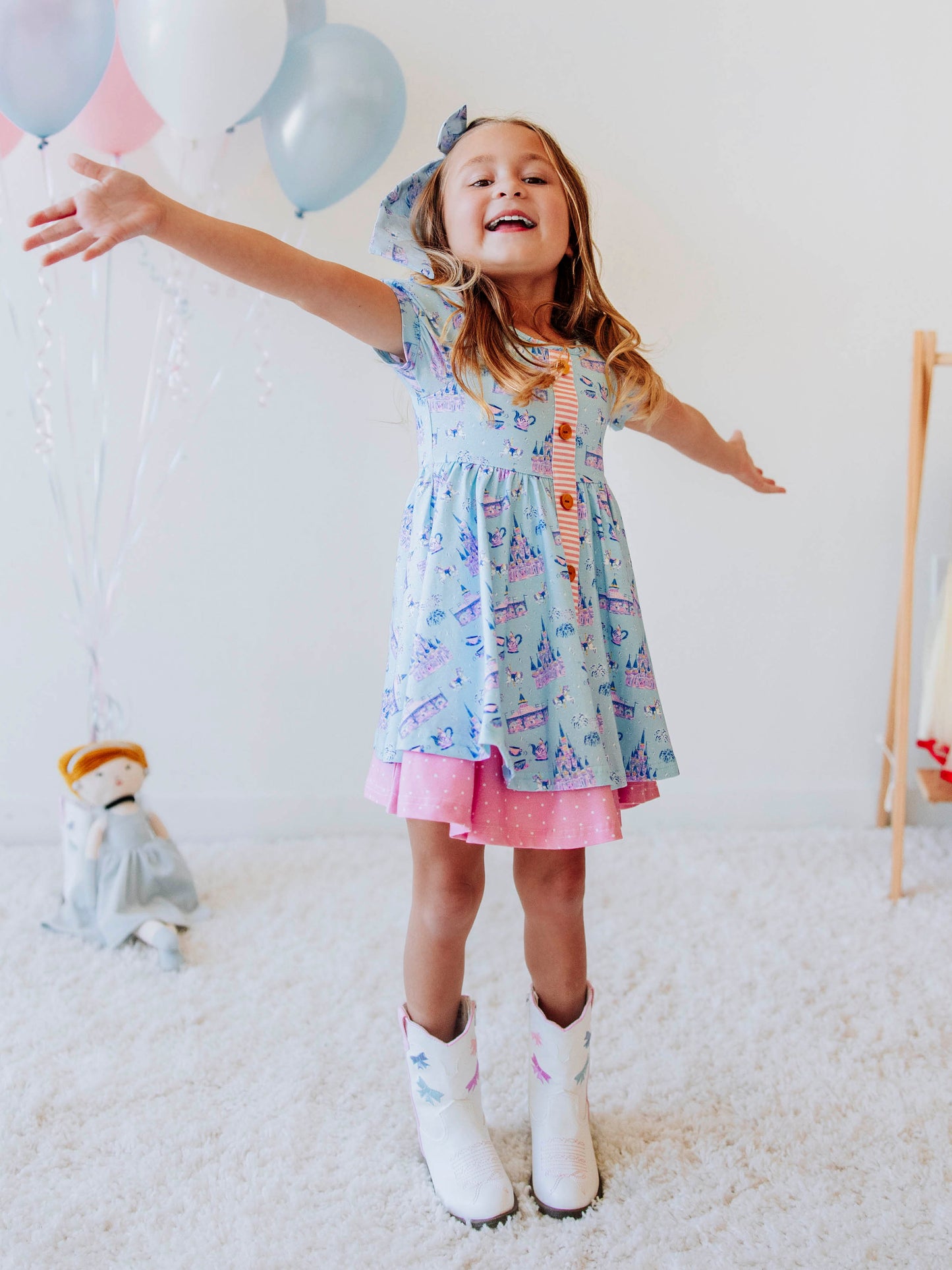 Bring a little fairytale charm to her day with our Most Magical Prim Dress! This enchanting dress features our exclusive Most Magical print — a whimsical pattern filled with castles, teacups, and dreamy pastel details. Designed with a sweet button-down front, short puff sleeves, and a full twirl skirt trimmed in pink polka dots, it’s perfect for playdates, park adventures, and magical memories.