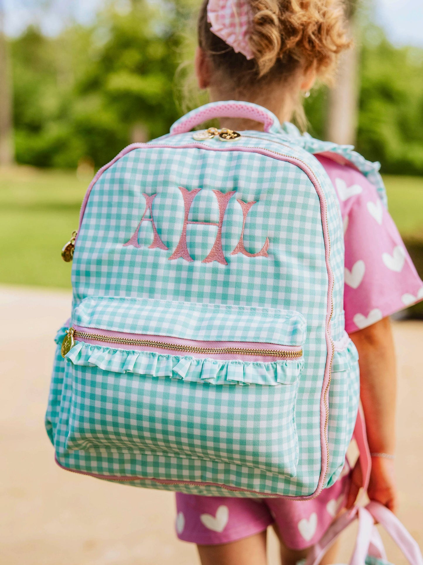 Girl wearing mint green gingham backpack with custom embroidery