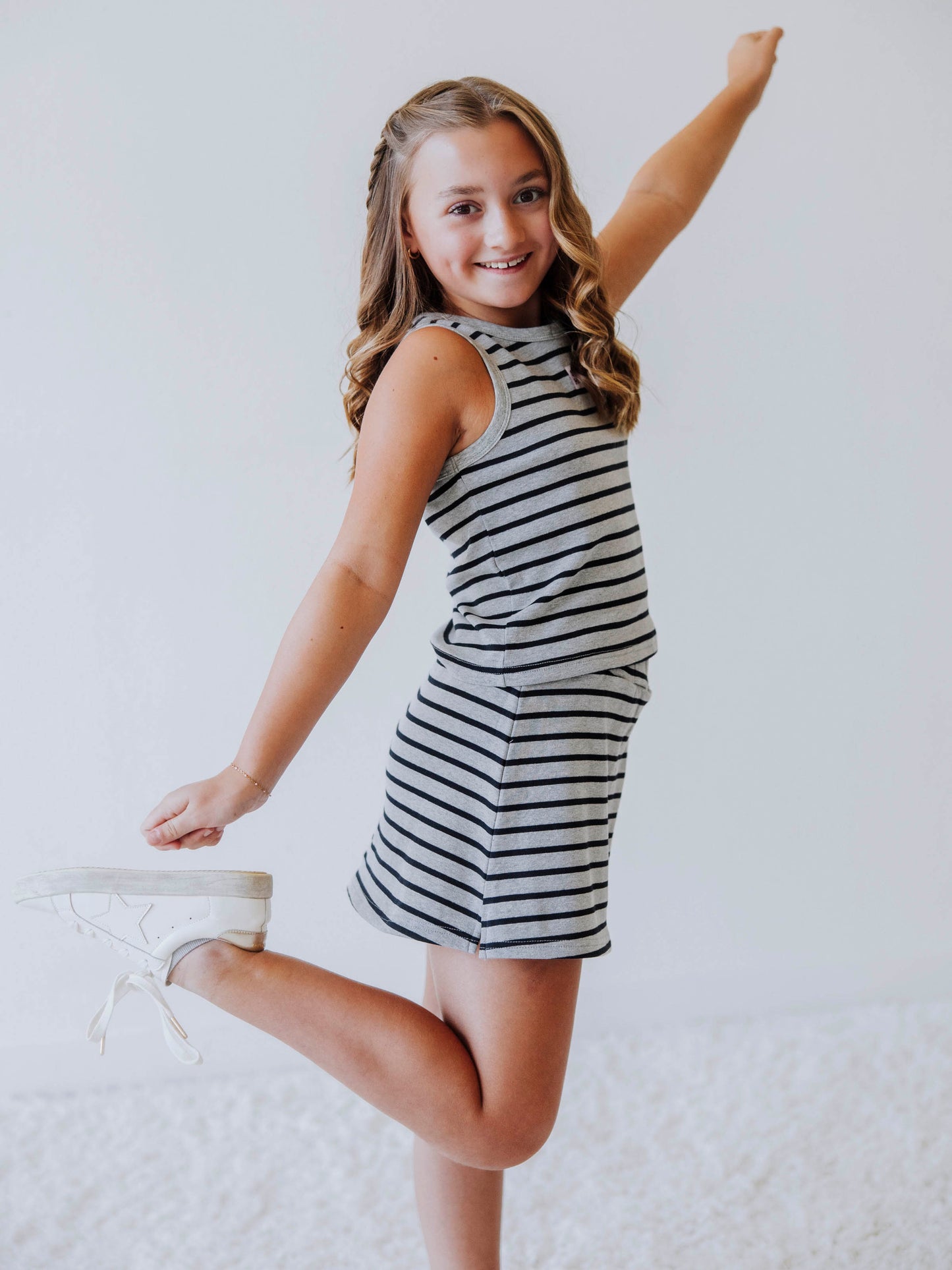 Posing model wearing a navy and gray, two piece skort set. Model is wearing white shoes. 