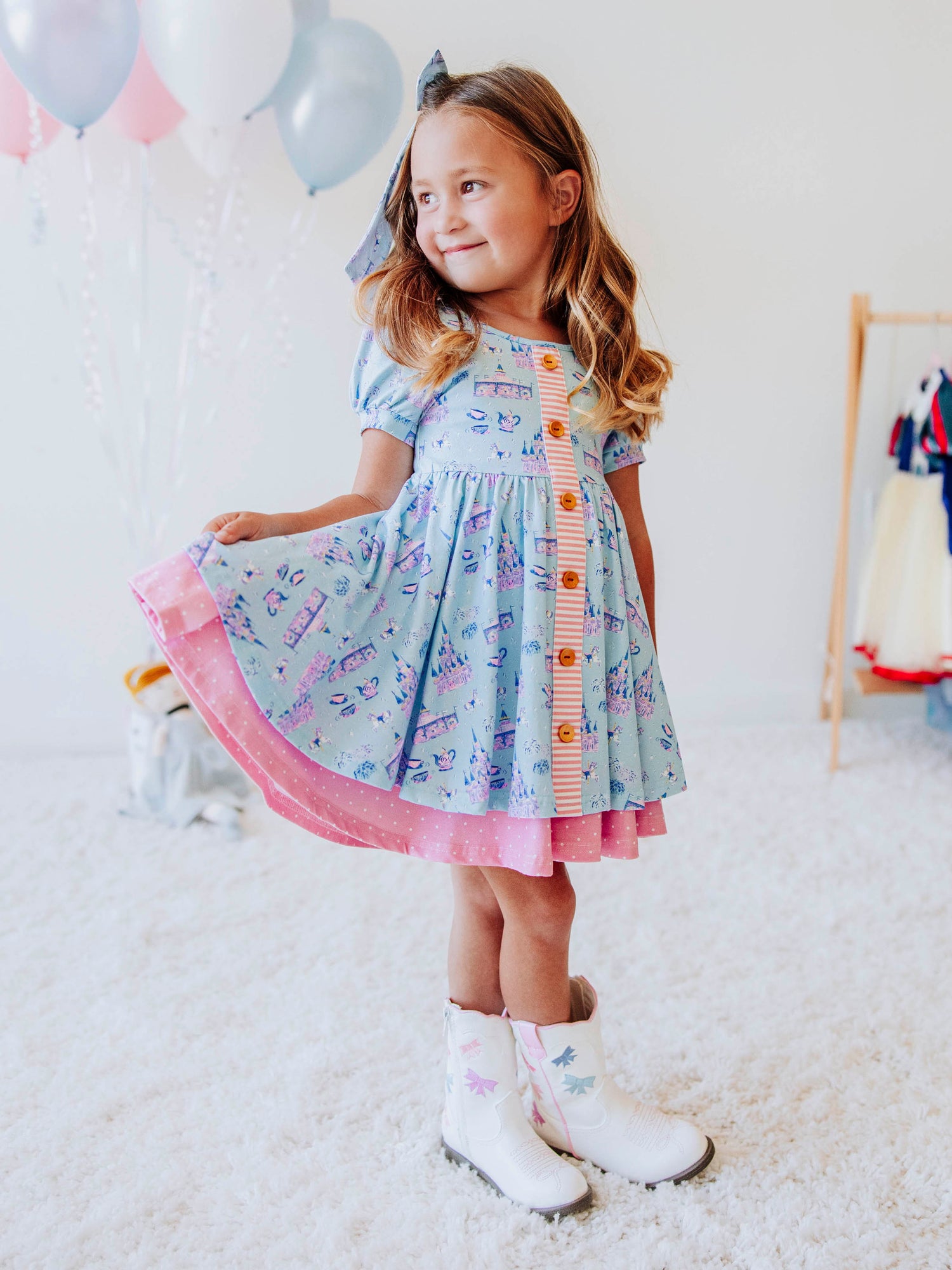 Bring a little fairytale charm to her day with our Most Magical Prim Dress! This enchanting dress features our exclusive Most Magical print — a whimsical pattern filled with castles, teacups, and dreamy pastel details. Designed with a sweet button-down front, short puff sleeves, and a full twirl skirt trimmed in pink polka dots, it’s perfect for playdates, park adventures, and magical memories.