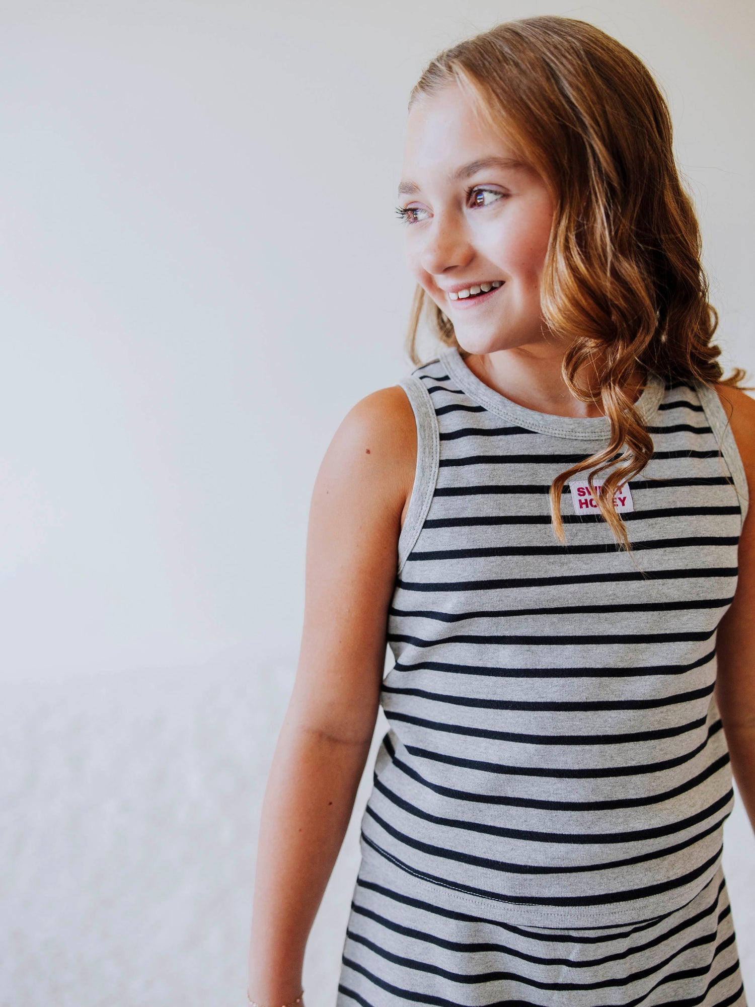 Posing model wearing a navy and gray, two piece skort set. There is a stitched red and white Sweethoney tag centered on middle of shirt. 