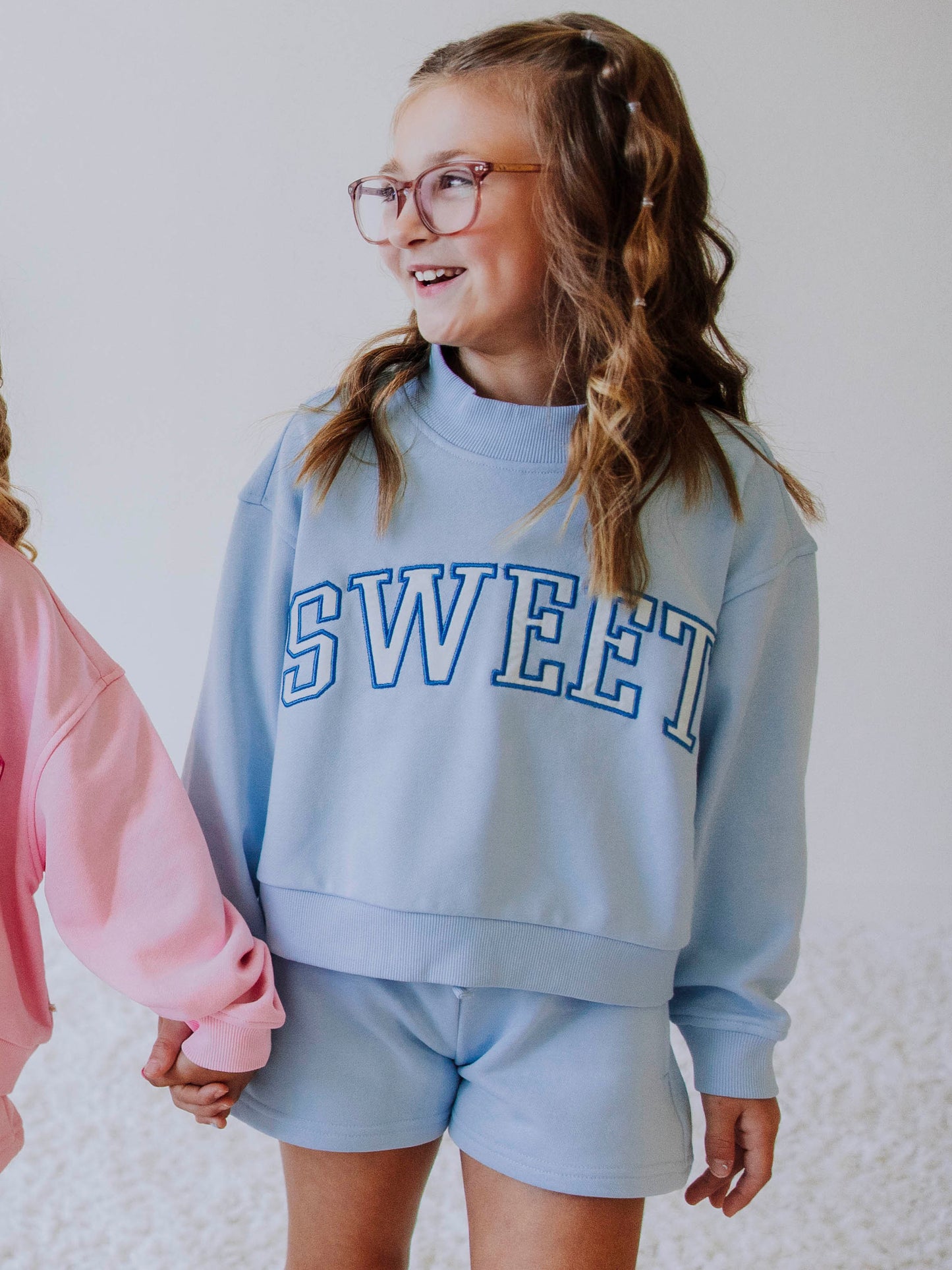 Model wearing a light blue two piece jogging set. Top says SWEET and the bottoms are the same color blue as top. 
