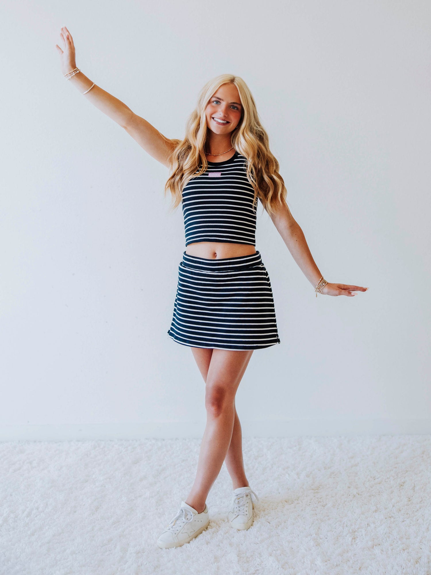 Model wearing a navy and white striped skort set. Top has a Sweethoney stitched logo tag in the middle of chest