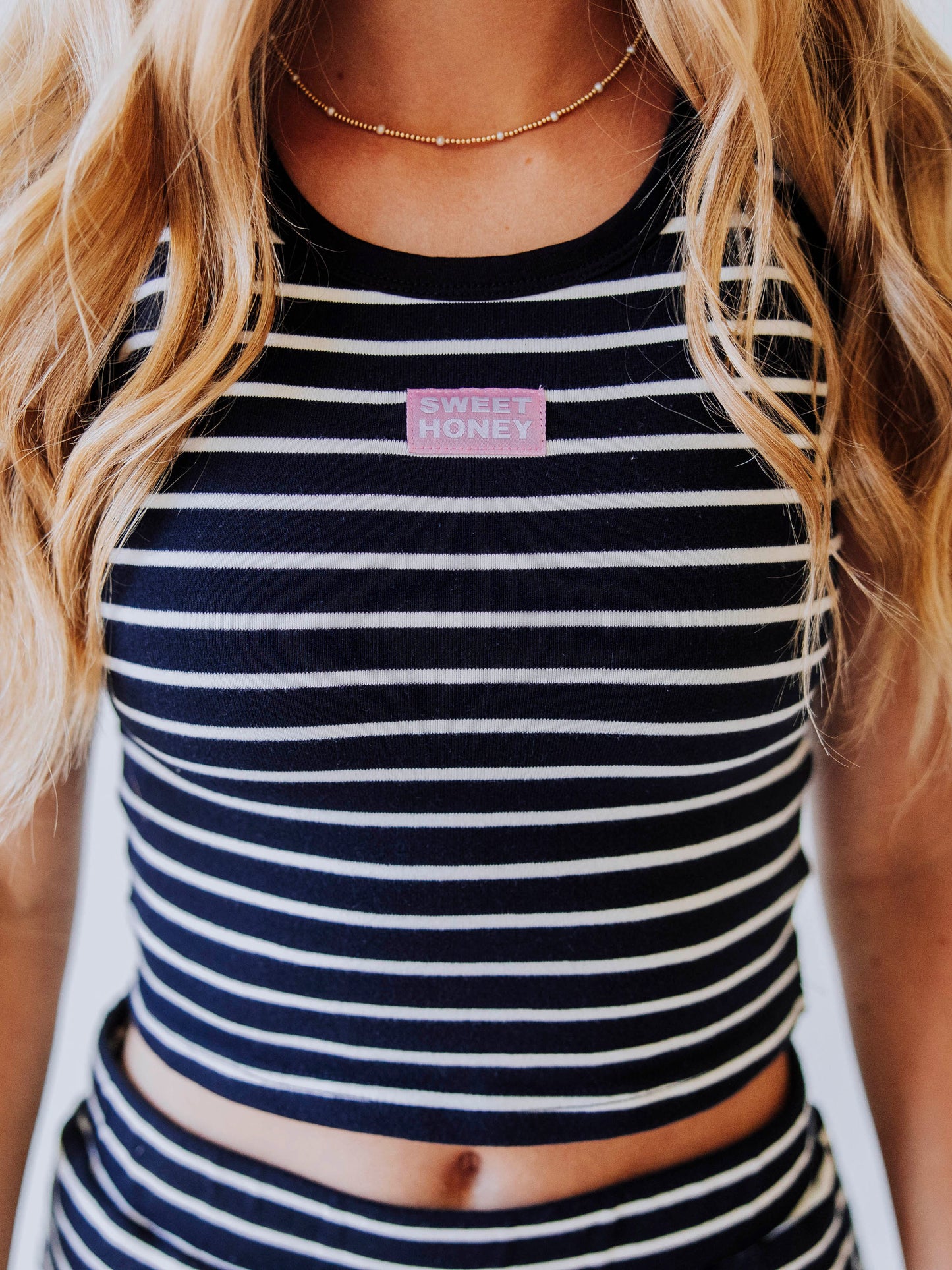 Model wearing a navy and white striped skort set. Top has a Sweethoney stitched logo tag in the middle of chest