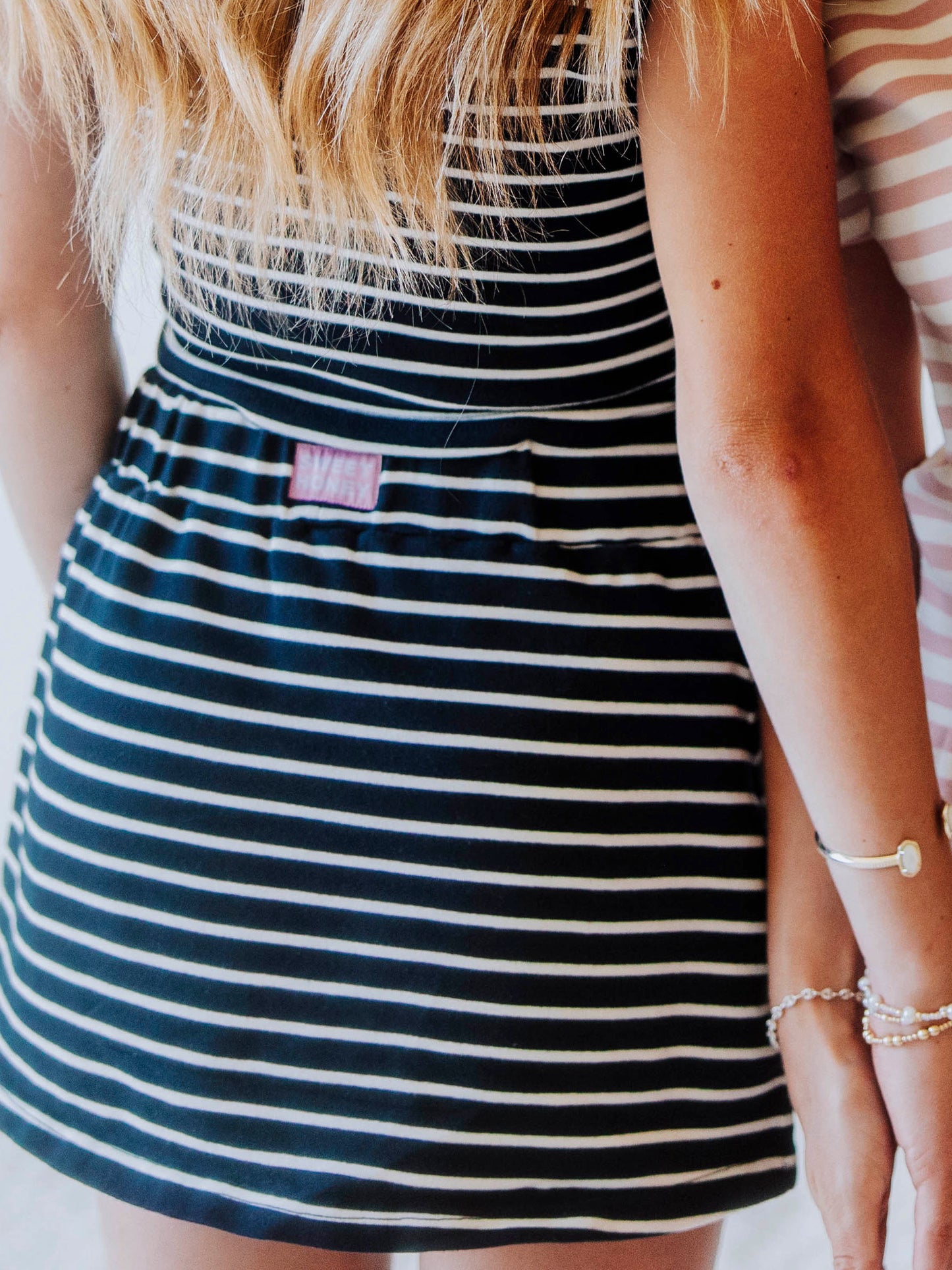 Close up shot of the back of a navy and cream colored skort. Picture shows a sweethoney logo stitched on back of waistband