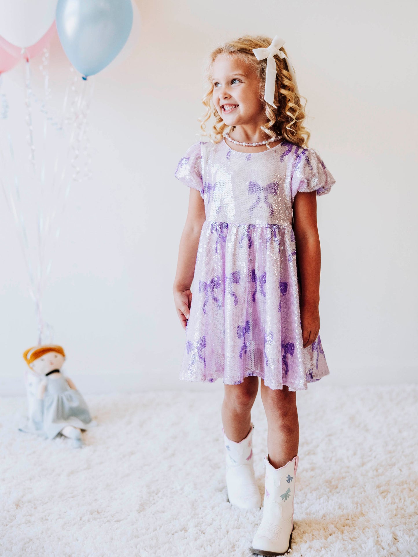 Let her sparkle and shine in our Lavender Sequin Bow Dress, a dazzling piece made for twirls, parties, and magical memories! Designed with shimmering lavender sequins and dainty bow details throughout, this girls’ sequin party dress captures the perfect mix of sweetness and sparkle.
The soft interior lining keeps her comfortable, while the puff sleeves and gathered skirt add a touch of classic charm. Perfect party dress, holiday dress and sparkle dress for any occasion! 