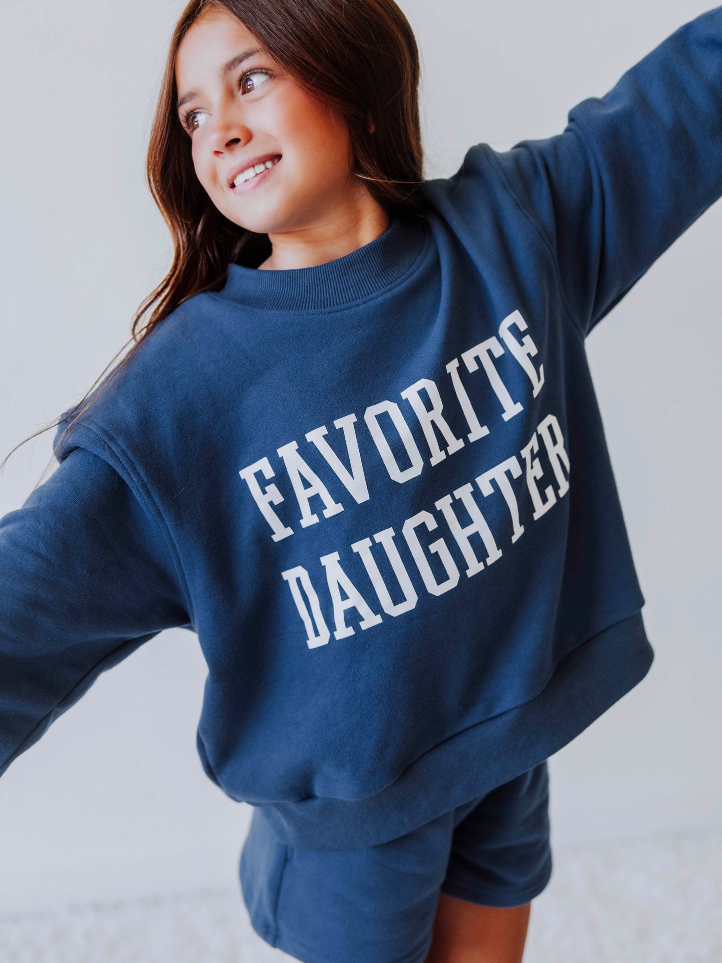 Model is wearing a two piece, navy sweat set that has FAVORITE DAUGHTER on the front in white vinyl letters. 