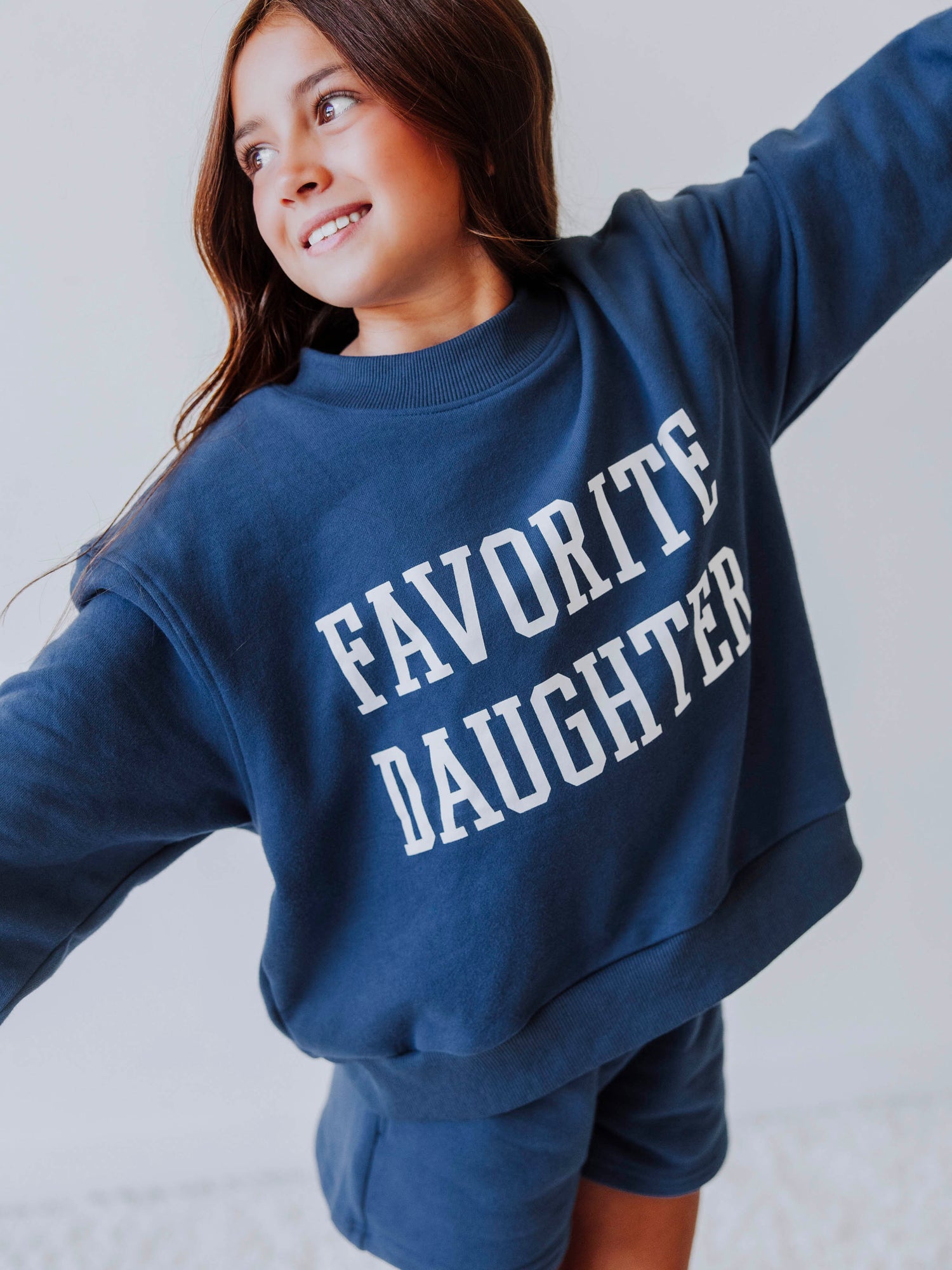 Model is wearing a two piece, navy sweat set that has FAVORITE DAUGHTER on the front in white vinyl letters. 