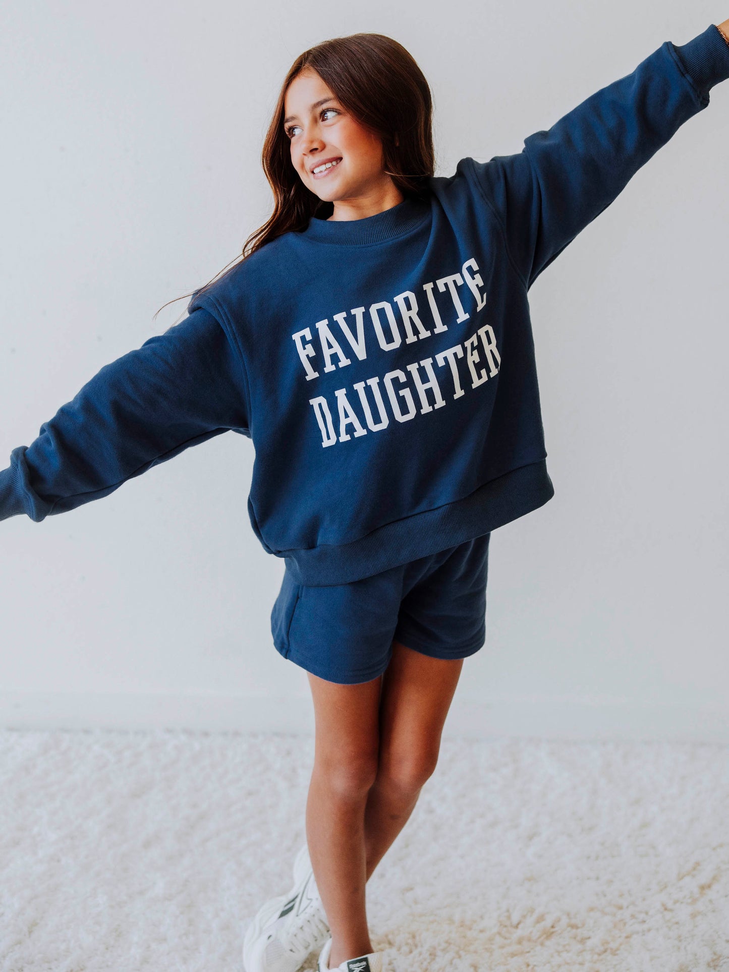 Model is wearing a two piece, navy sweat set that has FAVORITE DAUGHTER on the front in white vinyl letters. 