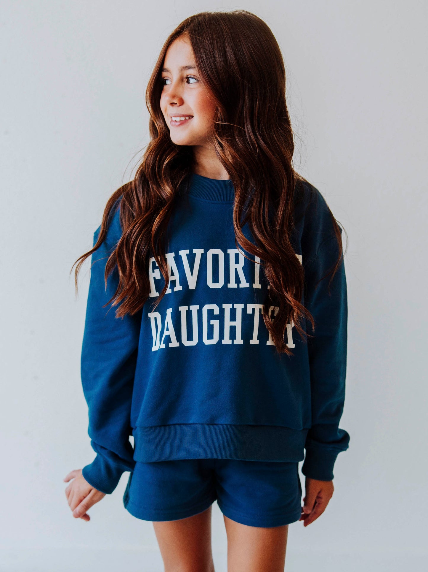 Model is wearing a two piece, navy sweat set that has FAVORITE DAUGHTER on the front in white vinyl letters. 