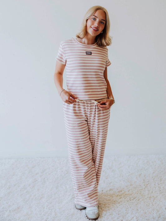 Model is wearing a pink and ivory striped pant set. Top has a stitched SweetHoney logo tag centered on chest. 