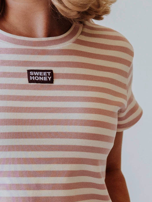 Close up of stitched on SweetHoney logo tag on chest of pink and ivory top