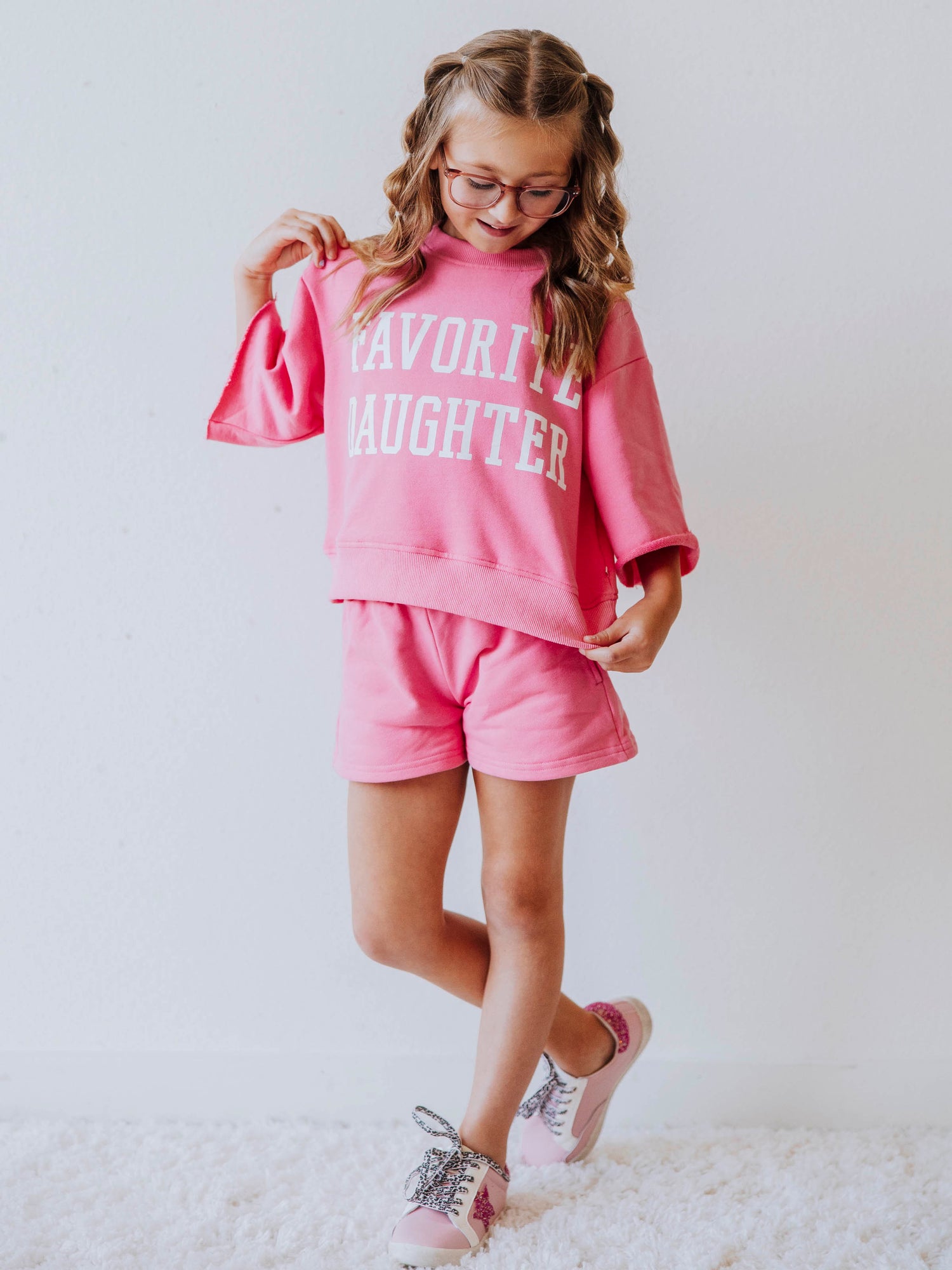 Model is wearing a two-piece, pink sweat set that has bell hemmed sleeves and the top has FAVORITE DAUGHTER in white vinyl lettering. 