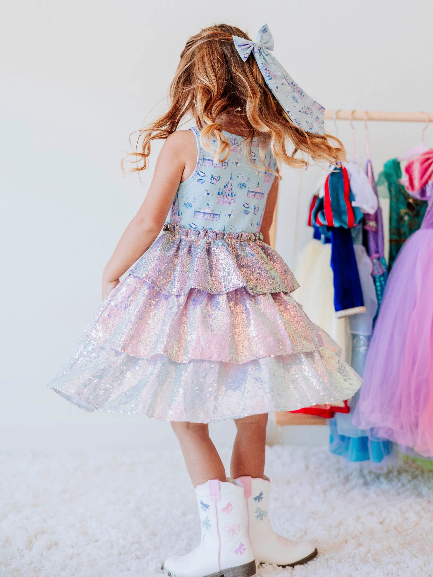 Make every day feel like a fairytale in our Most Magical Tiered Sparkle Dress! This enchanting girls’ dress features our signature “Most Magical” print bodice — filled with dreamy castles, carousels, and whimsical details — paired with a tiered iridescent sequin skirt that shimmers with every twirl. Designed for comfort and style, it’s perfect for holiday photos, birthday parties, or any moment that calls for a little extra sparkle. The soft lining ensures an itch-free fit, while the sleeveless design makes