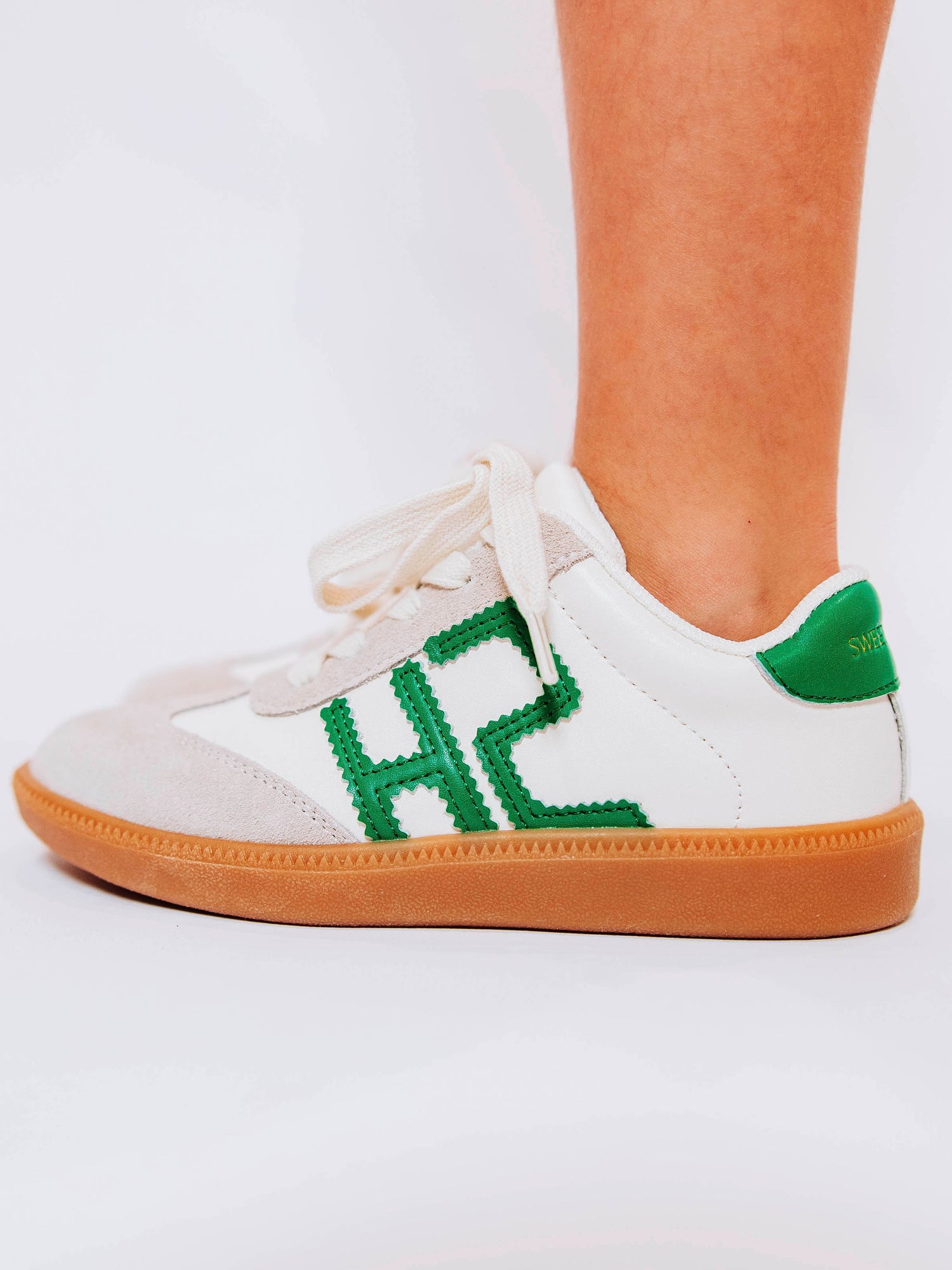 Fresh, fun, and full of SweetHoney style — our Signature Sneakers in green and white are the perfect mix of comfort and charm! Featuring our bold “SH” SweetHoney logo, soft suede accents, and durable gum soles, these boutique kids’ sneakers are designed for everyday adventures. Whether paired with twirl dresses or playtime outfits, they’re the ultimate blend of fashion and function for little trendsetters on the go.