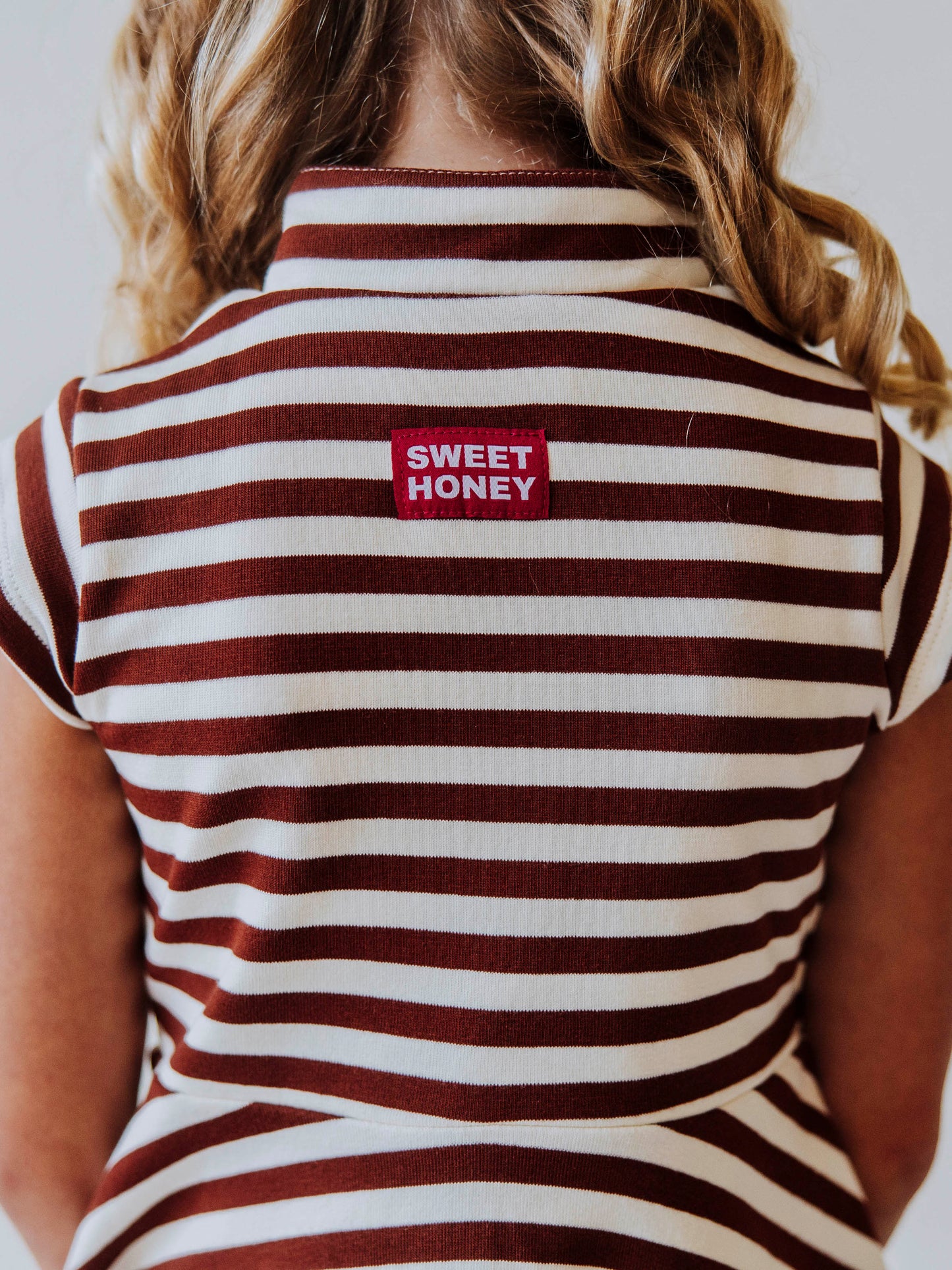 Backside of brown and ivory striped dress. Shown is a sweethoney logo tag stitched at back of dress. 