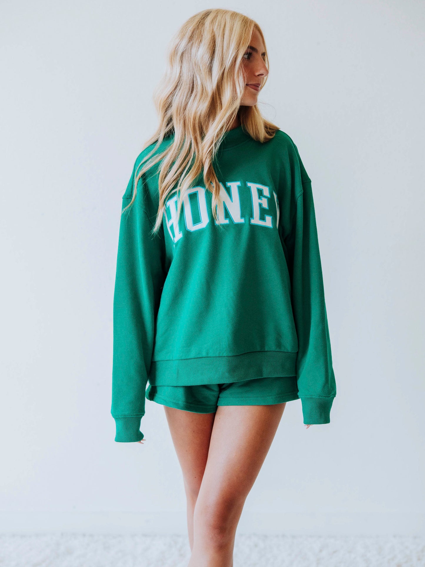 Girl wearing a teal two piece set. Top says HONEY on the front. Shorts are same teal color as top. 