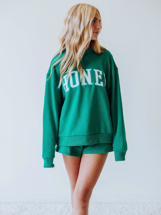 Girl wearing a teal two piece set. Top says HONEY on the front. Shorts are same teal color as top. 