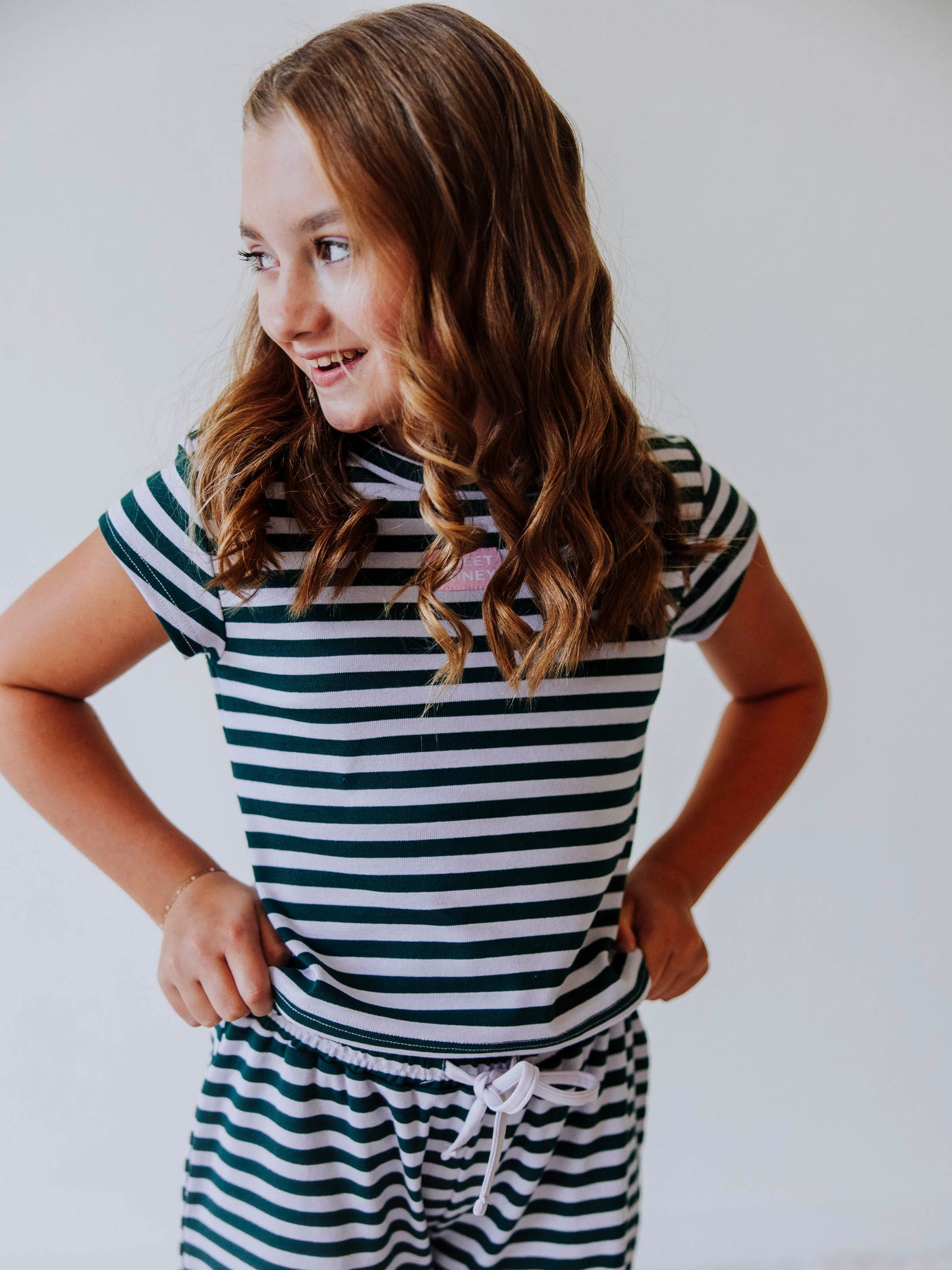 Girl is wearing a two piece, green and gray striped pant set. 