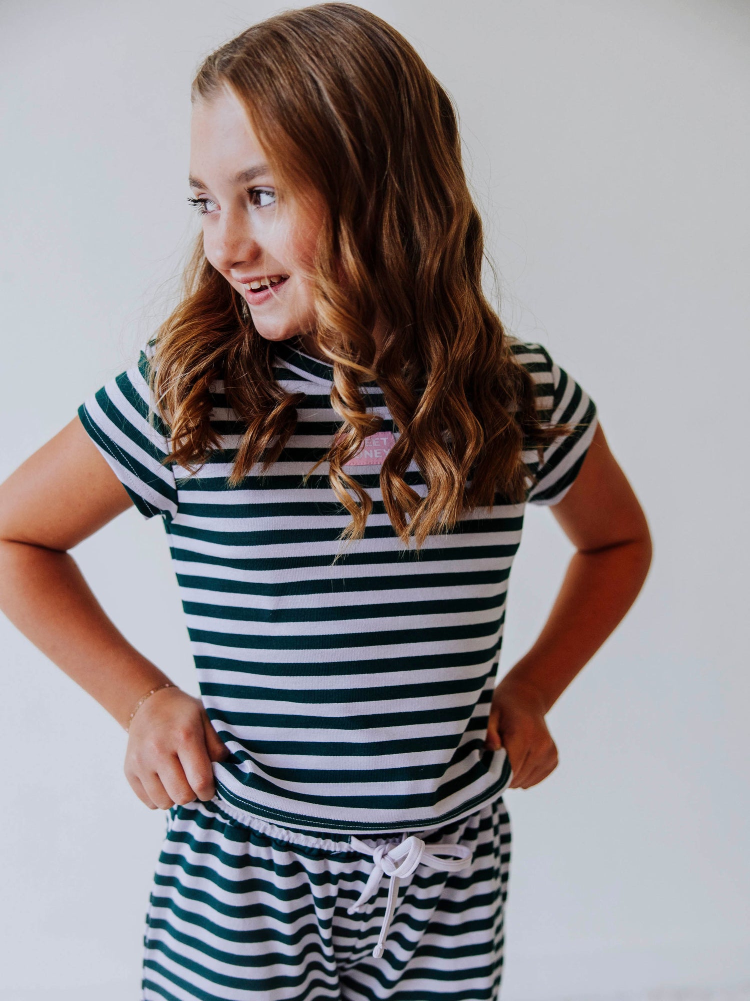 Girl is wearing a two piece, green and gray striped pant set. 