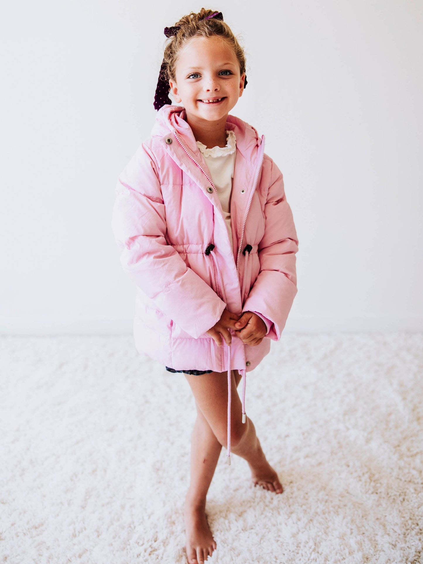 Keep her cozy and cute all season long in our Pink Puffer Jacket — the perfect blend of warmth and style! This soft, quilted jacket features a full zipper closure with a button placket, ensuring extra protection from chilly winds. Hidden front pockets keep little hands warm (or treasures tucked away), while the adjustable waist toggle allows for the perfect, comfortable fit. Designed in a beautiful blush pink hue, this girls’ puffer jacket pairs effortlessly with any winter outfit for a look that's fun!