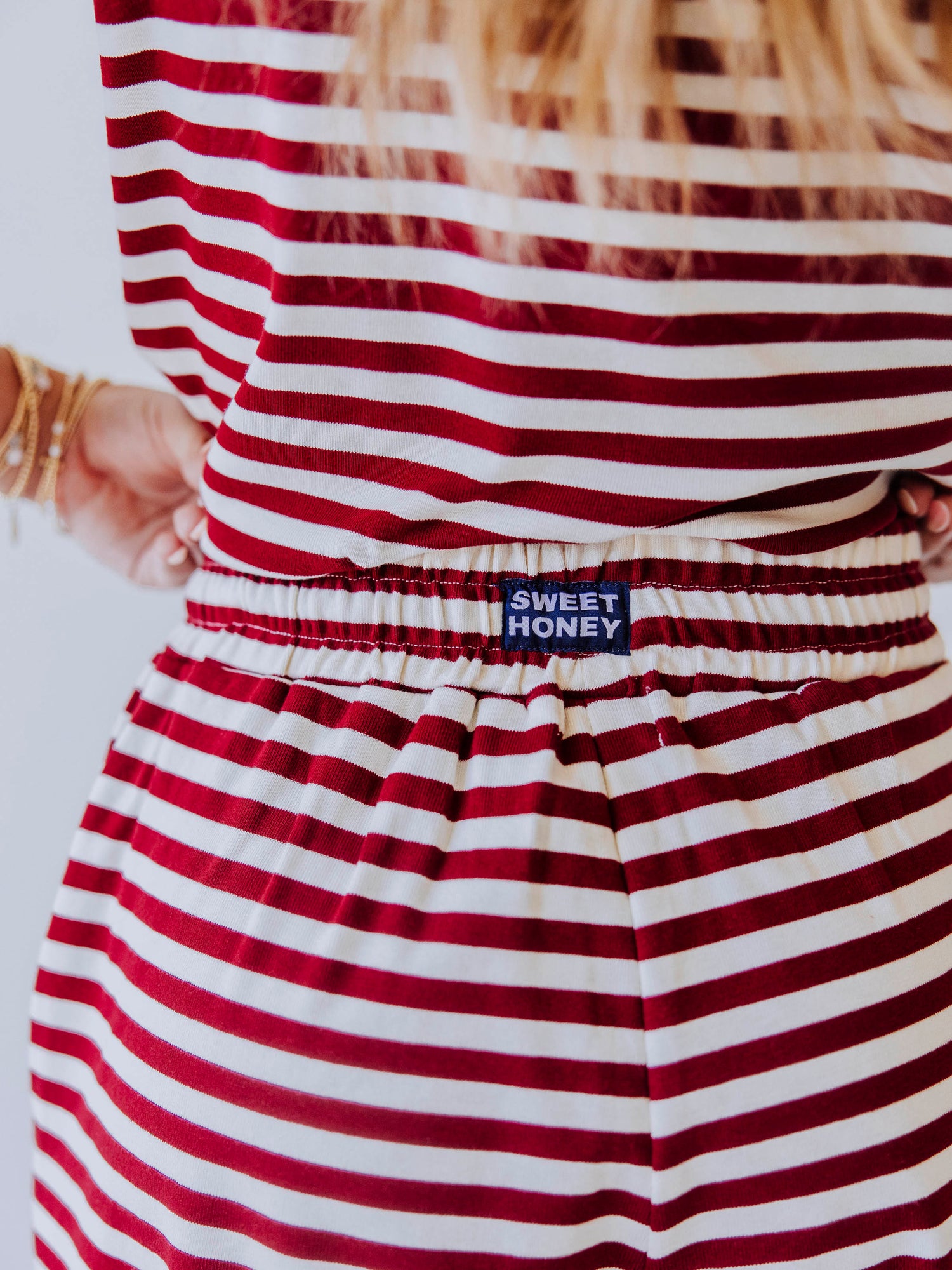 Close up of sweethoney stitched logo tag at back of crimson and ivory pant waistband
