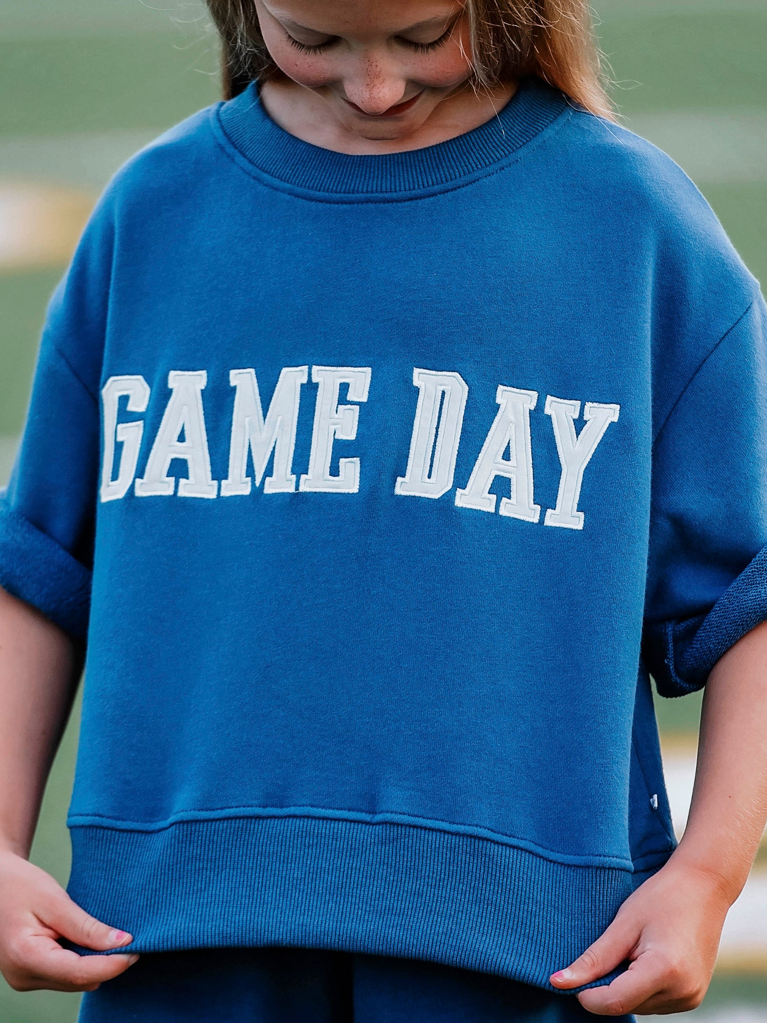 Girl outside wearing a two piece navy set that says GAME DAY on the front. 