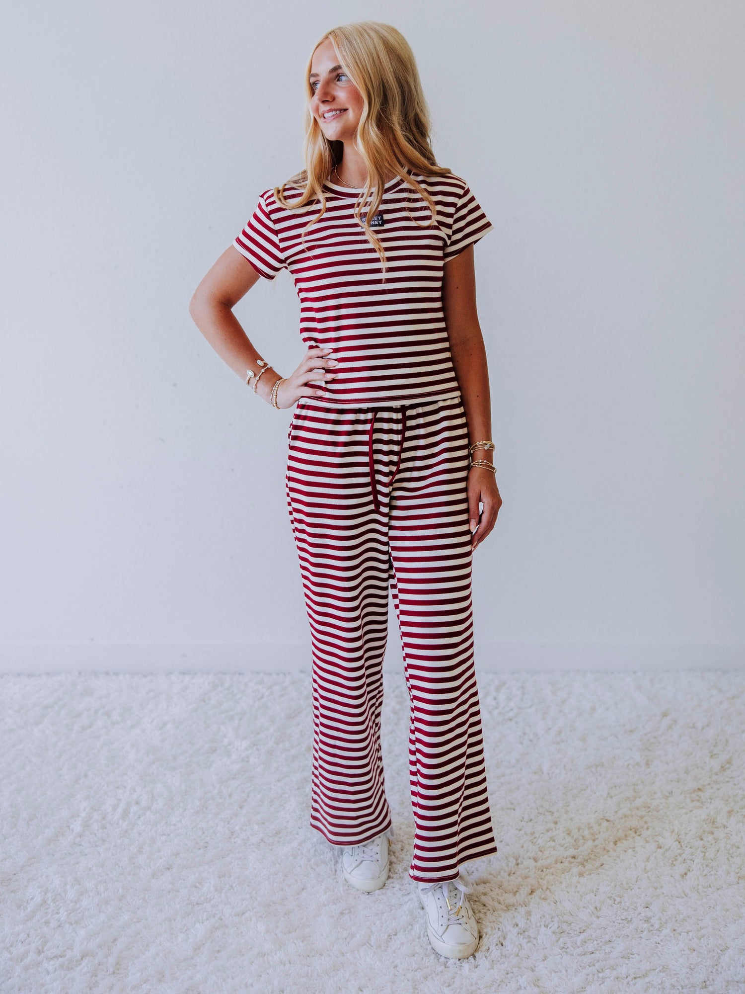 Model is wearing a crimson and ivory striped two-piece pant set. Top has stitched sweethoney logo tag at chest