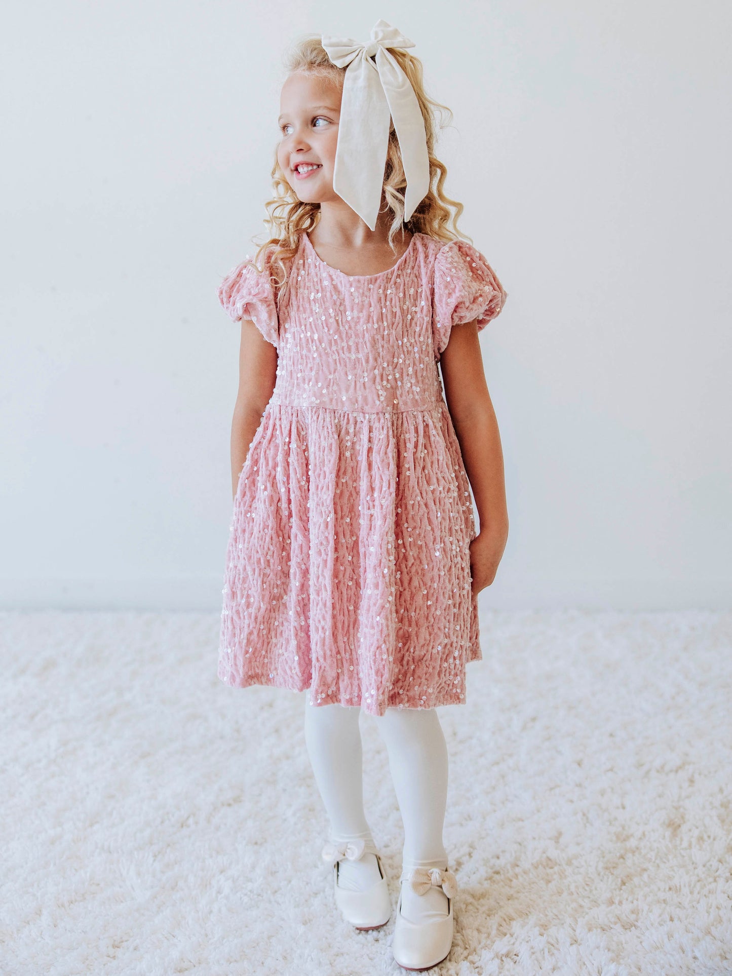 Make every moment shine in our Girls’ Sequin Sparkle Dress, designed for holiday parties, special occasions, and picture-perfect moments. Crafted from 100% polyester, this dress features a soft velvet-like texture that’s gentle on the skin and a smooth interior lining for all-day comfort. The fabric is covered in shimmering transparent sequins that catch the light beautifully, creating a dazzling effect with every twirl.
