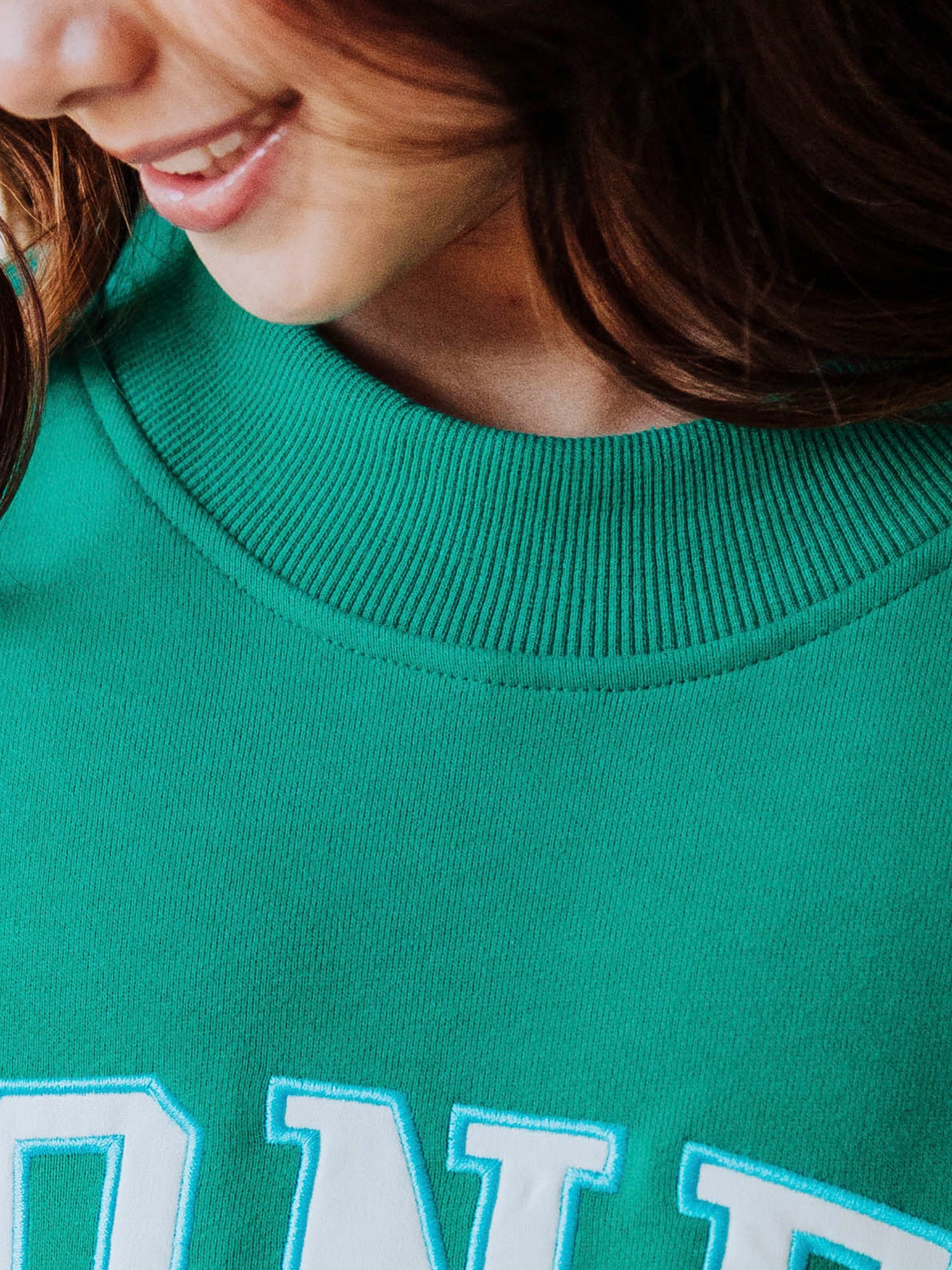 Close up of a teal mock neck top. Close up shows detail of the mock neck